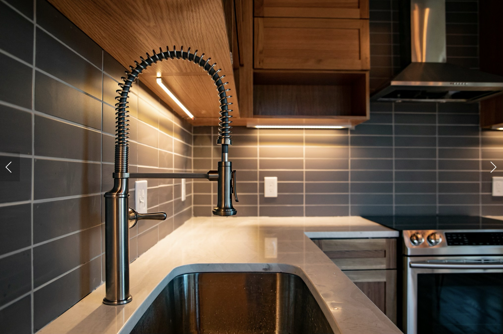 Detail from the Buildco portfolio: wood cabinetry, a tiled backsplash, and a sink with a spring-coil faucet.