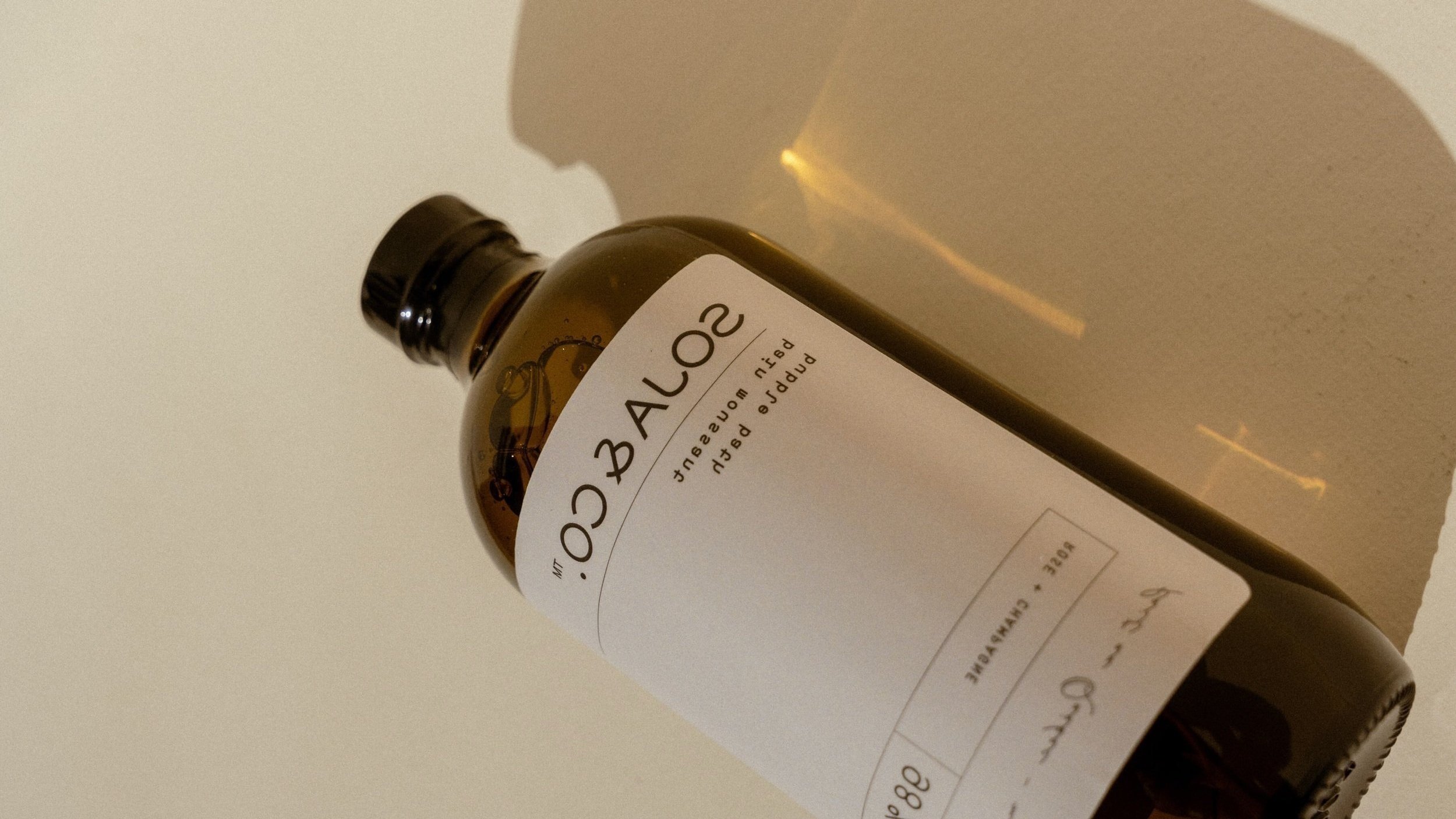 A brown glass bottle labeled 'Balão 50' with white label, lying on its side on a light-colored surface, casting a shadow.