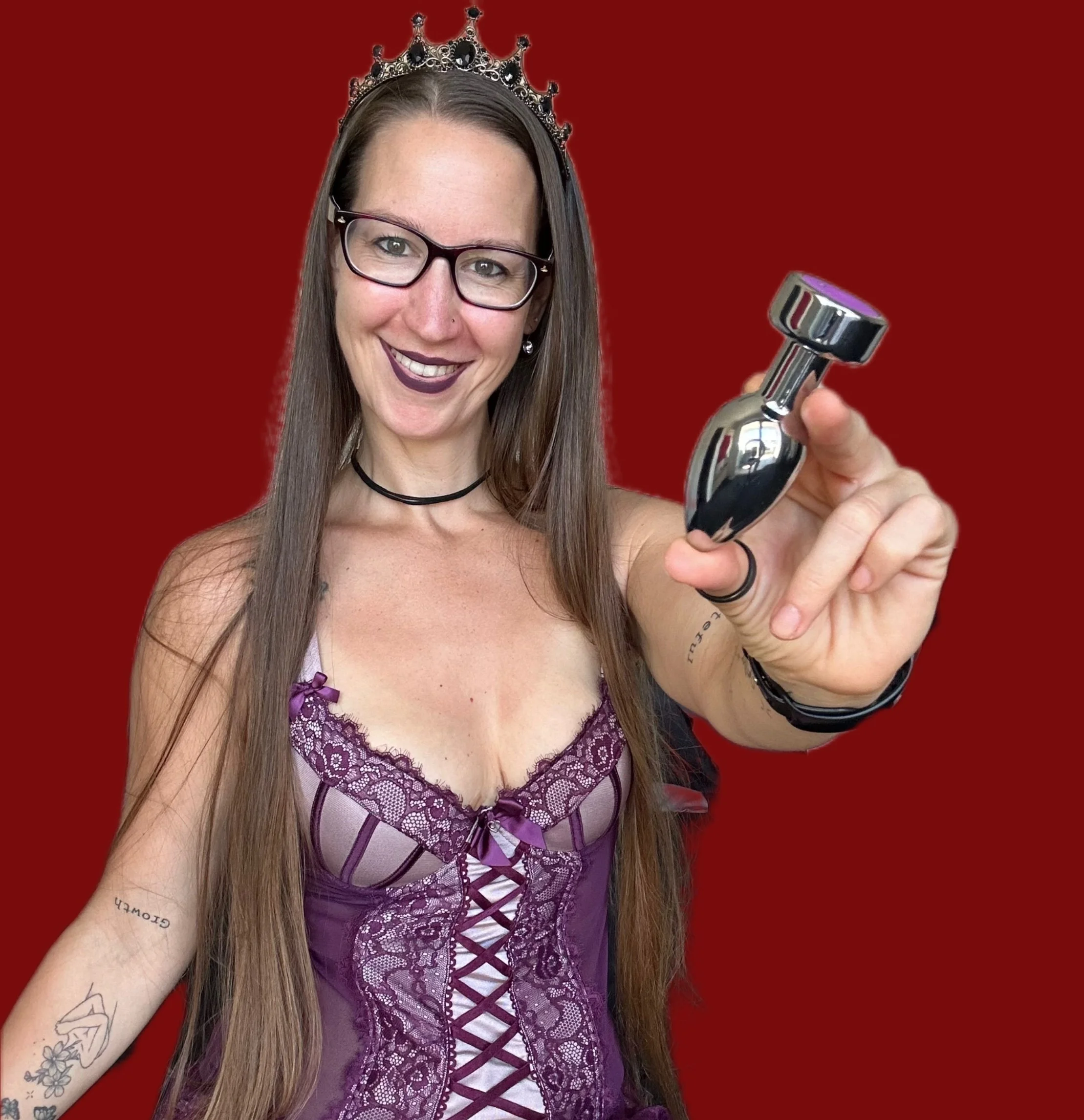 Pleasure Toy Queen Patricia is holding a vibrating steel anal plug wearing lingerie and her crown