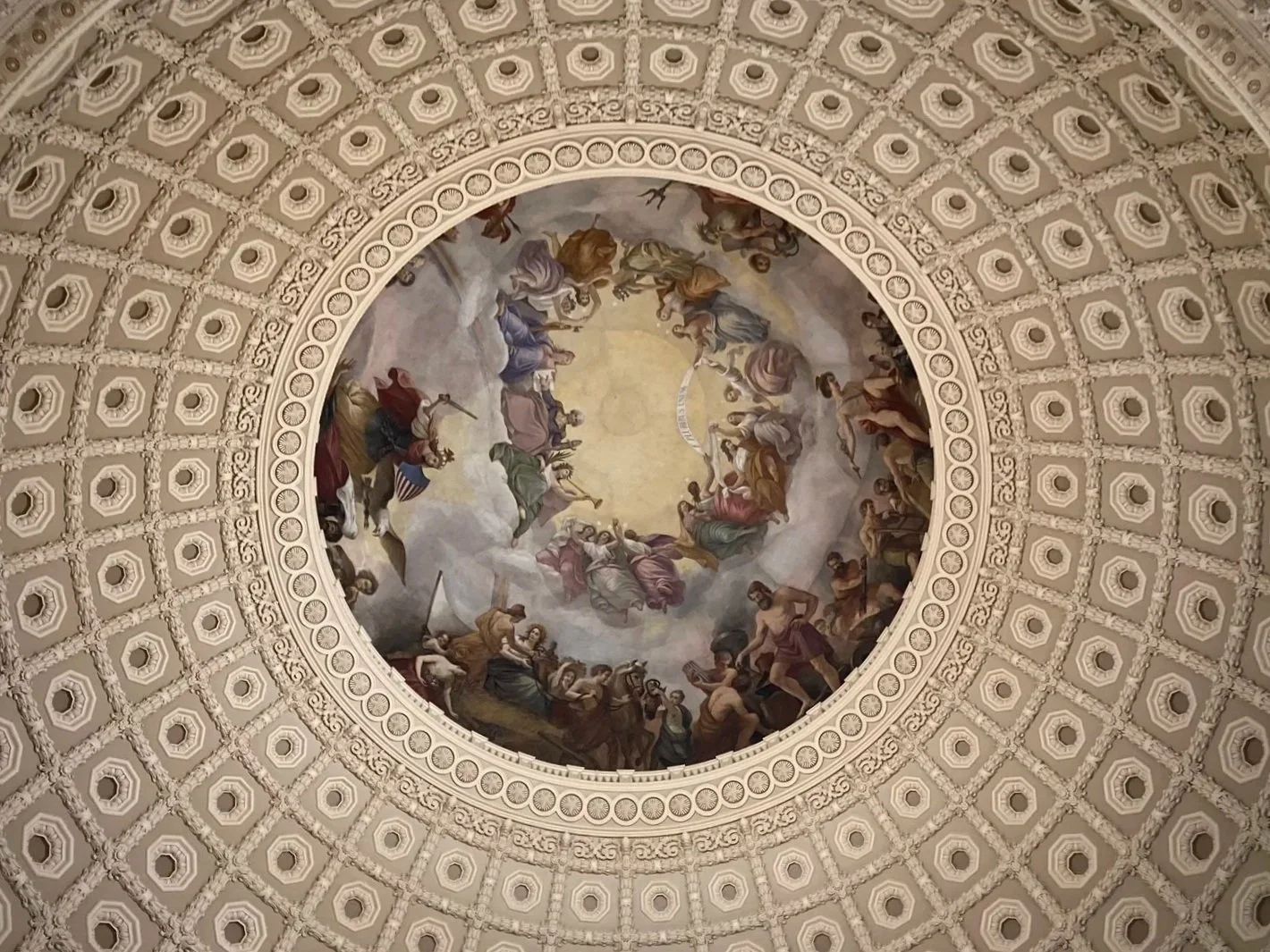 Ceiling fresco with angels and clouds inside a domed architectural ceiling.