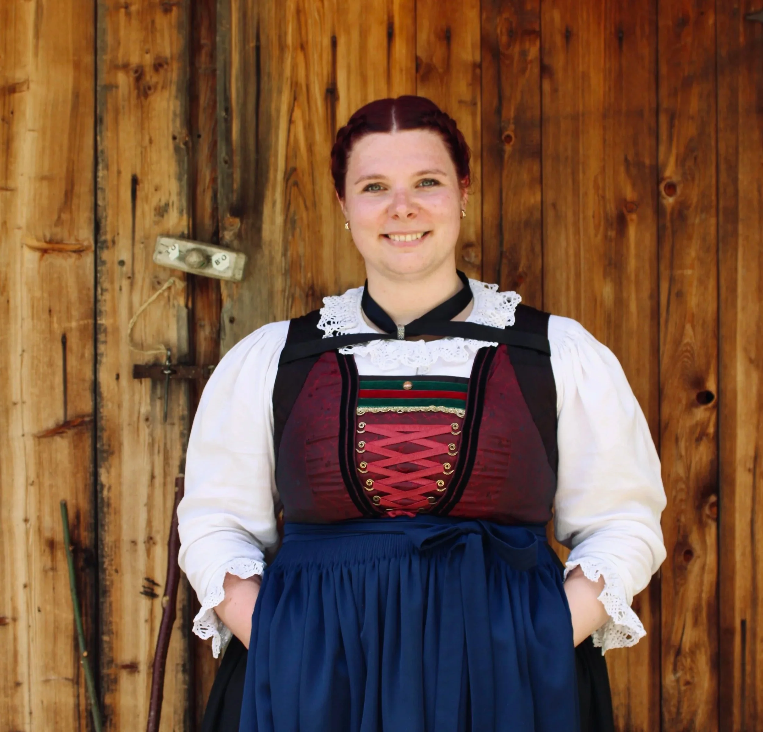 Junge Frau in traditioneller norwegischer Tracht vor einem curtain in einem Zimmer.