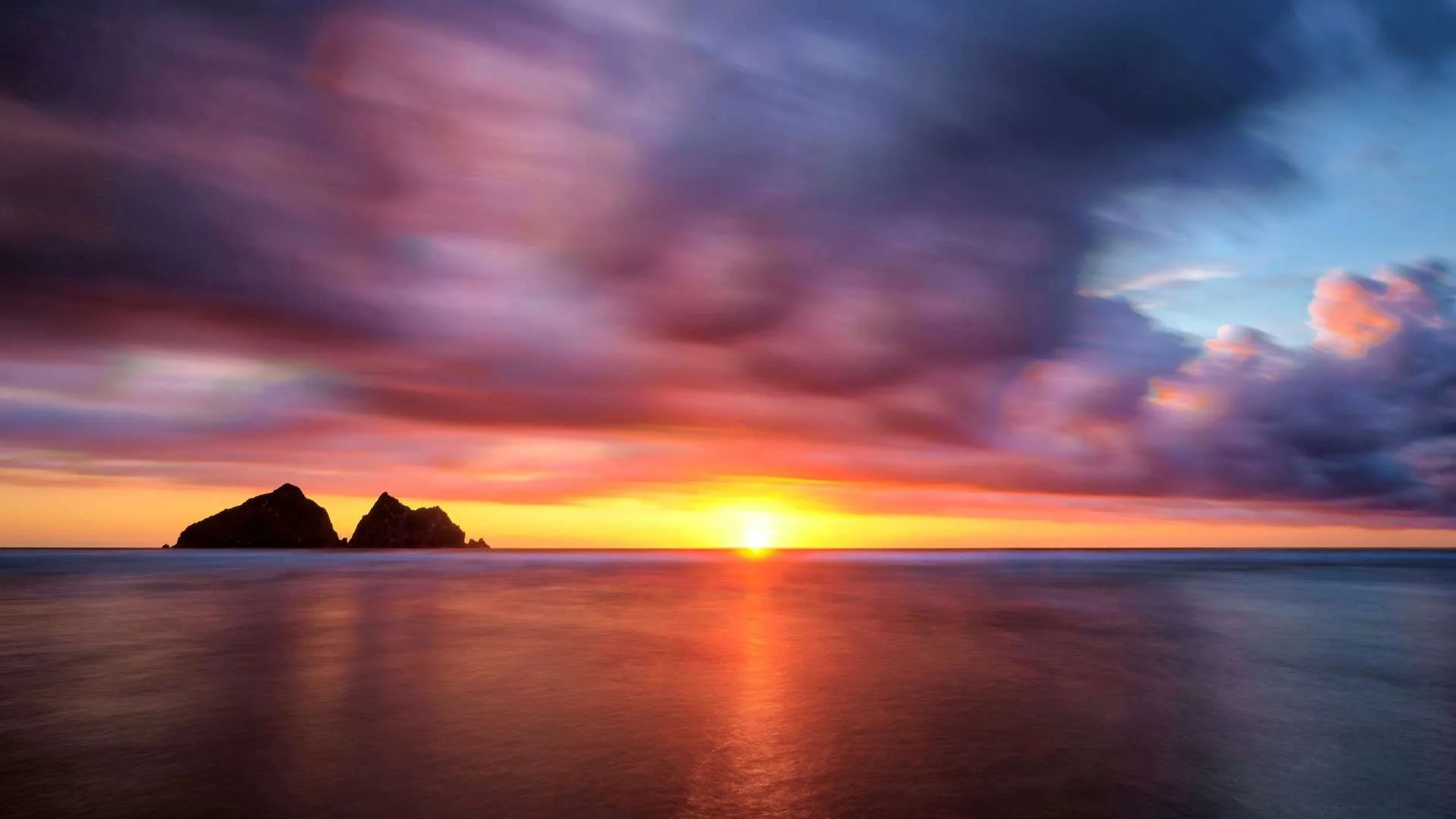 Holywell Bay: "Sunset view looking out over the serene waters and expansive sands of Holywell Bay."