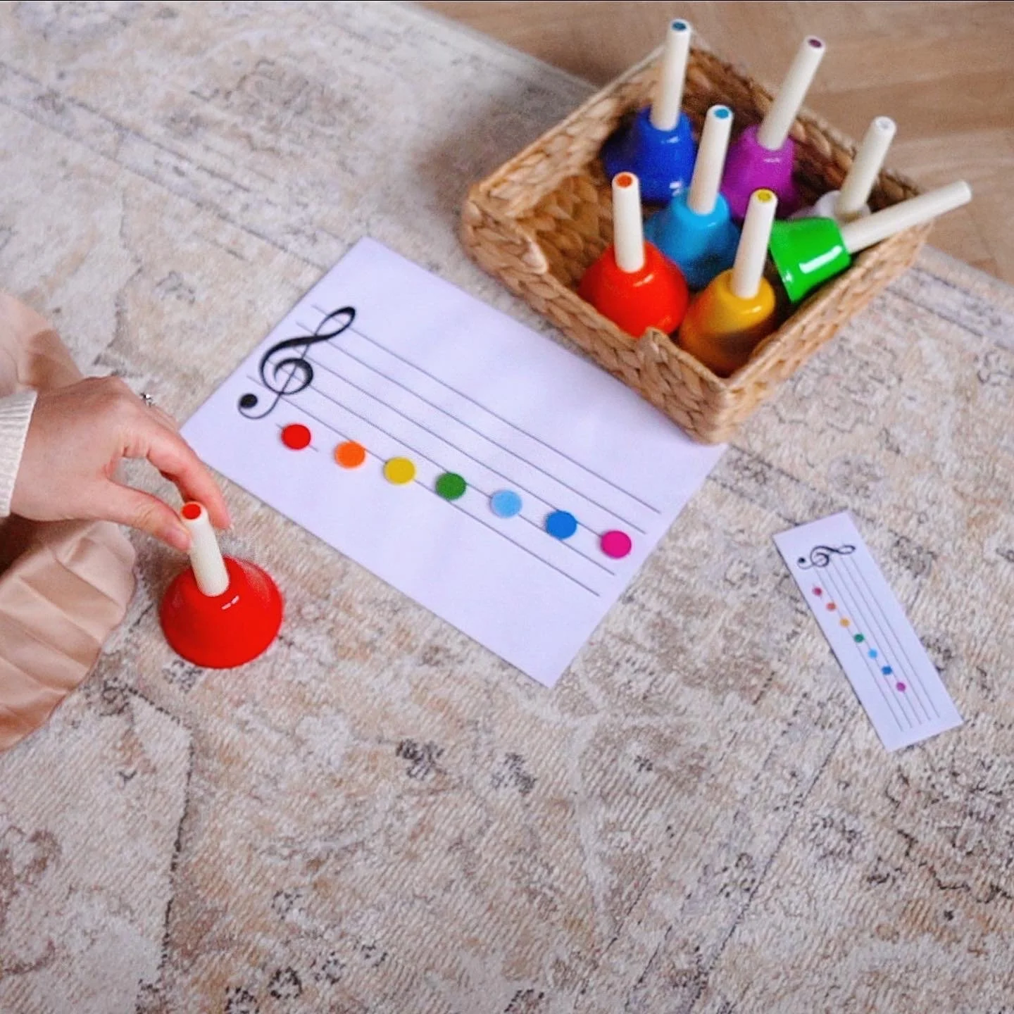 Colorful musical notes craft activity with painted bottles and paper music sheets on a table.