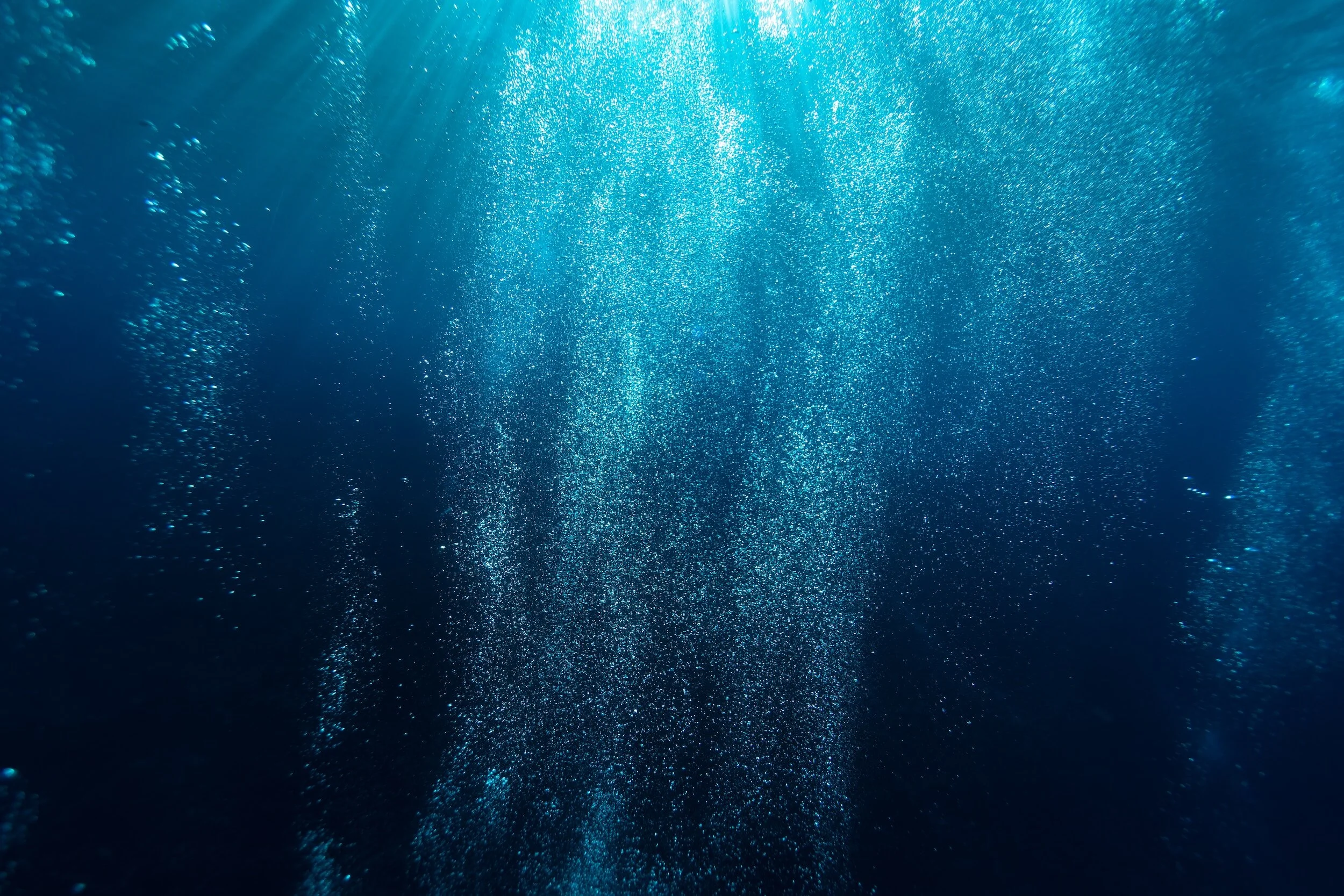Underwater scene with sunlight filtering through water, creating bright rays and small bubbles.