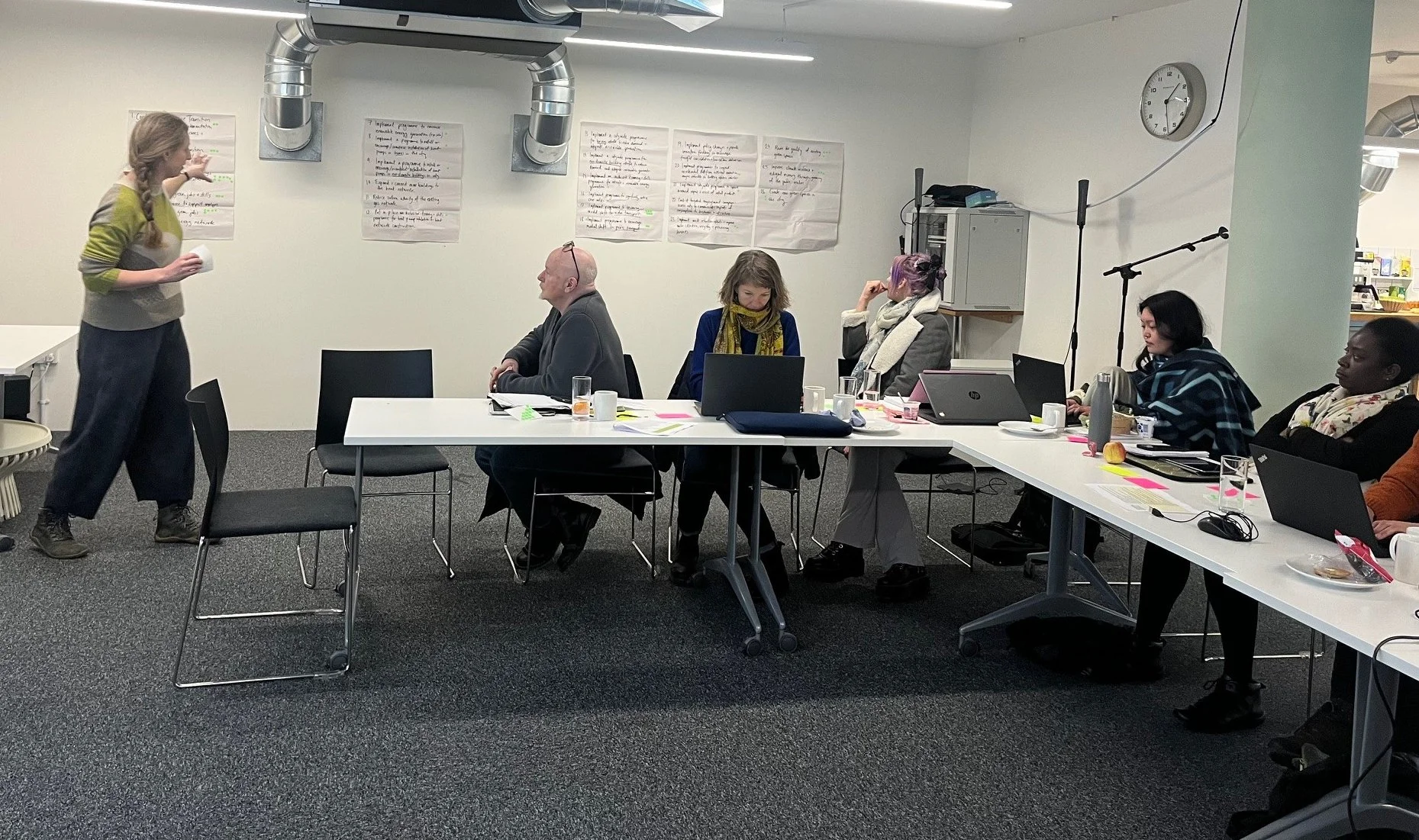 The panel members with Emilia, reviewing a proposal using flipcharts stuck to the wall.