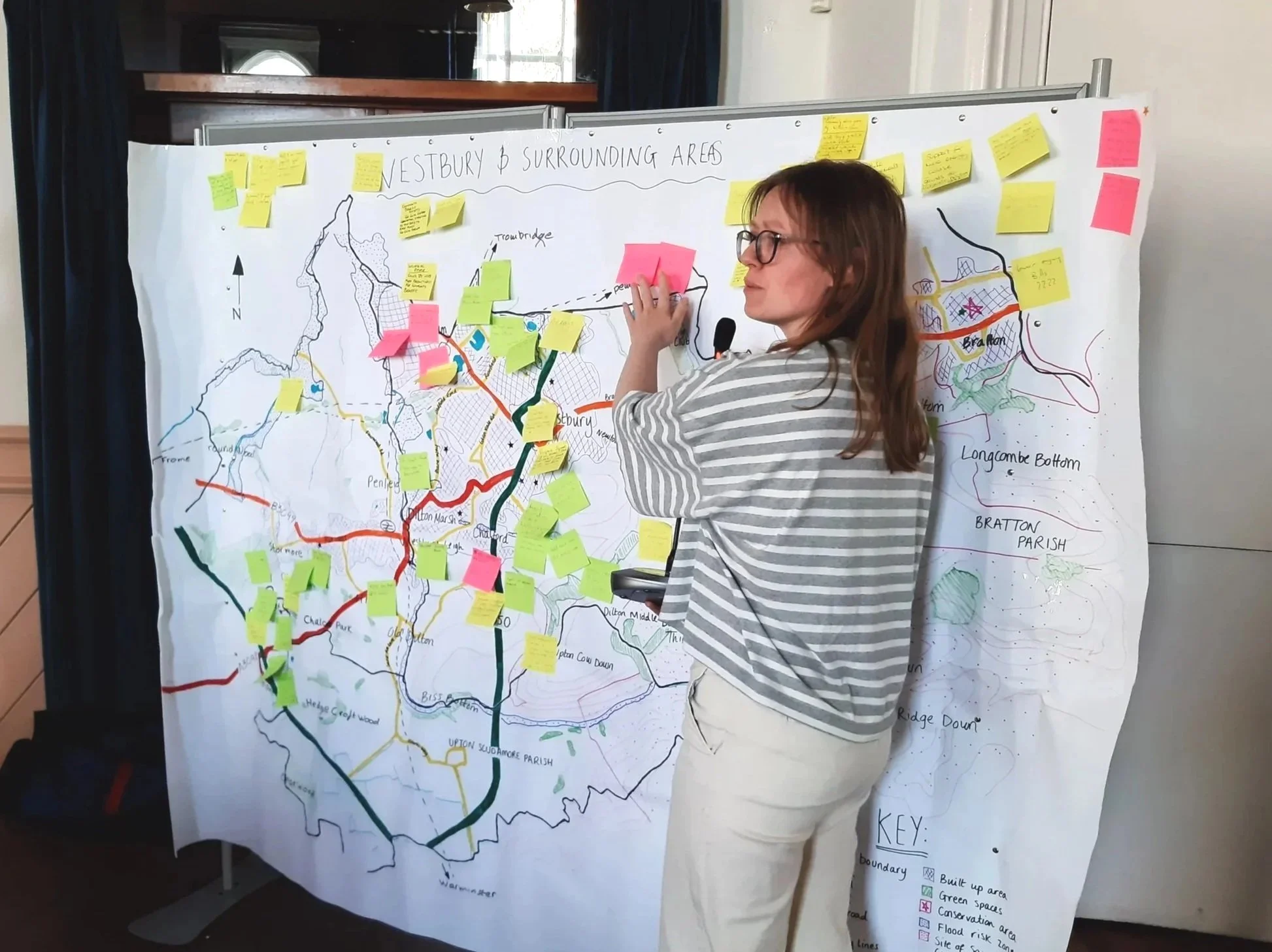 A person stands in front of a large map of Westbury and the surrounding areas. The map is dotted with yellow, pink, and green post-it notes.