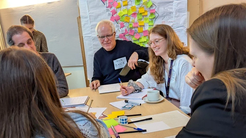 5 people discuss ideas round a table. 