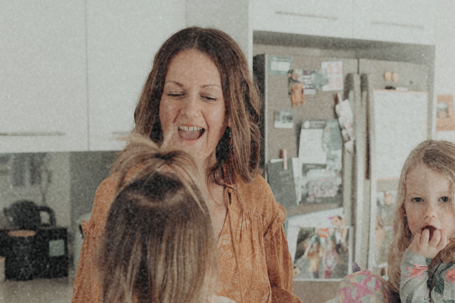 woman standing in her kitchen smiling at her child