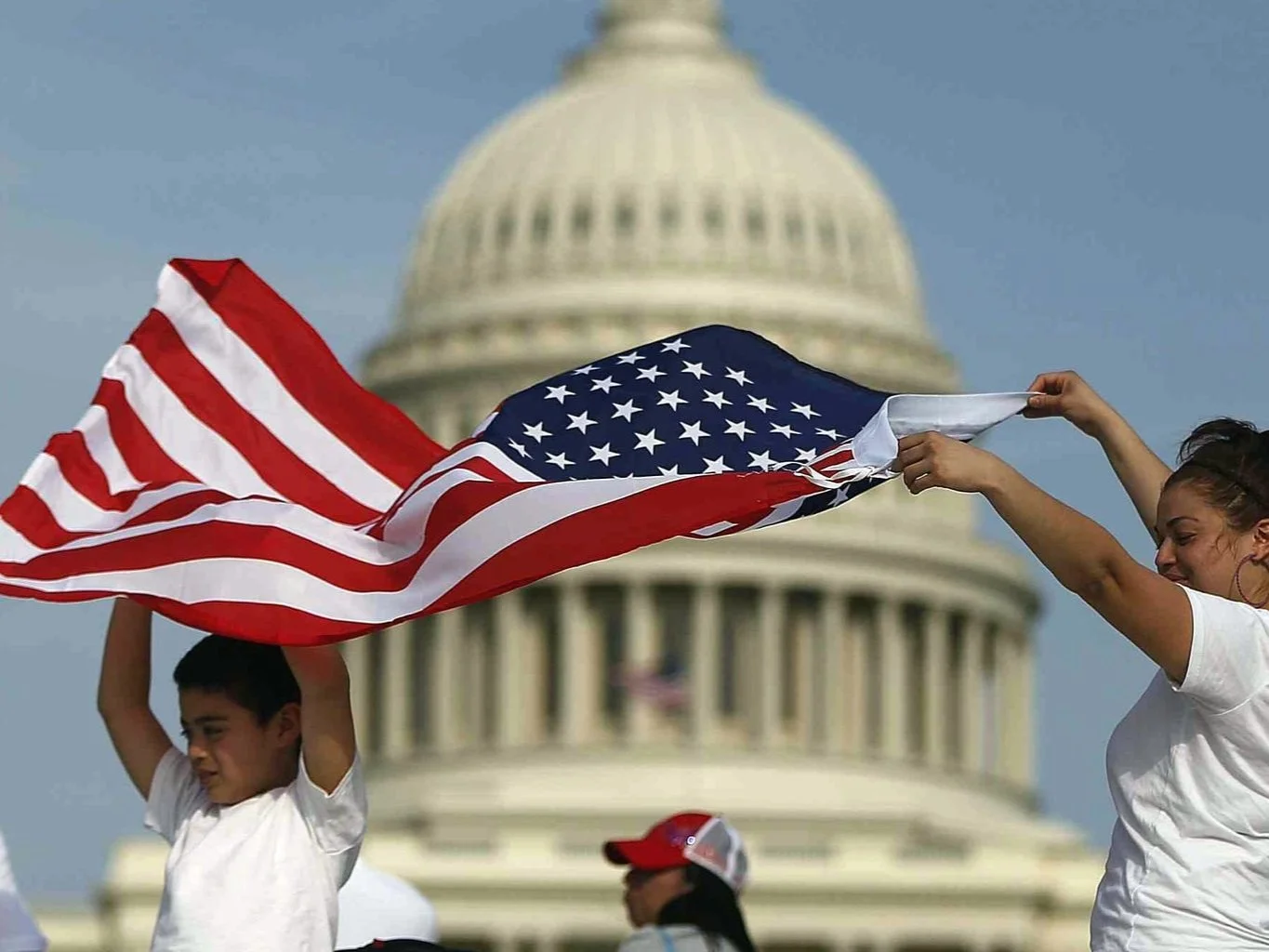 People holding the American flag in front of the U.S. Capitol building.