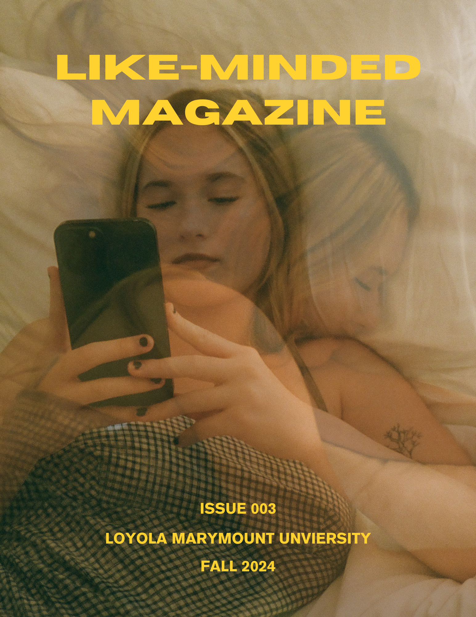 A person with long hair taking a selfie in a mirror, lying down on a bed or couch with beige sheets, with text overlaid that reads 'LIKE-MINDED MAGAZINE ISSUE 003 LOYOLA MARYMOUNT UNIVERITY FALL 2024' in yellow font.