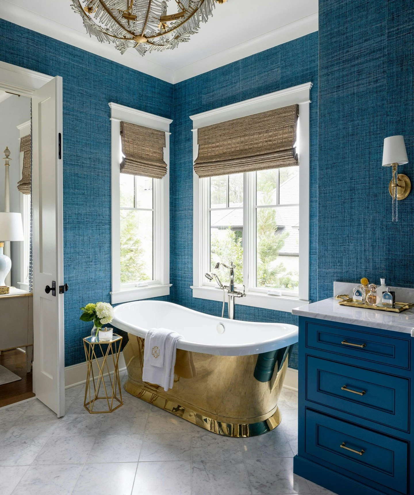 A brass-finished tub anchors this elegant master bath, offering a striking contrast to the organic grasscloth wallpaper. The coordinating hardware ties the space together for a cohesive look with an unexpected flair. ✨

Photographer: @ellis_creek_pho