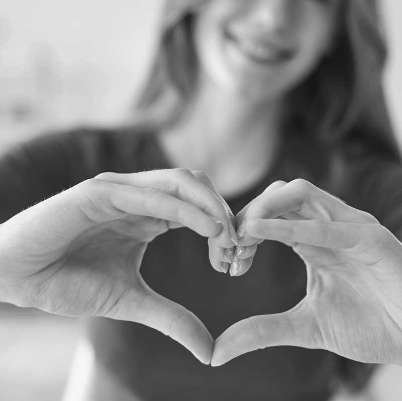 Employee at ACS a behavioral health care for people with disabilities smiling and forming a heart shape with their hands.