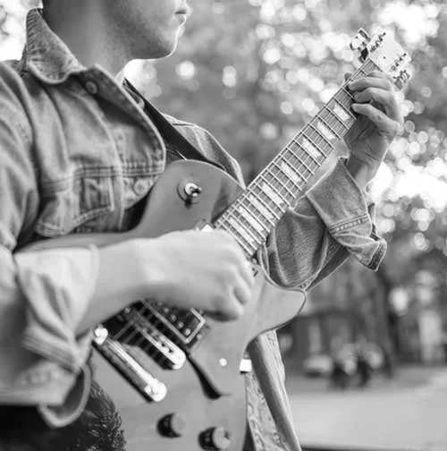 Person playing electric guitar outdoors on a sunny day during Crisis Stabilization for kids with autism in Redding, CA