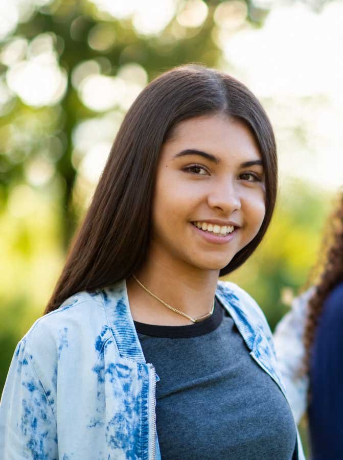 Young woman with long brown hair smiling outdoors receiving Behavioral Services with ACS in Redding, CA