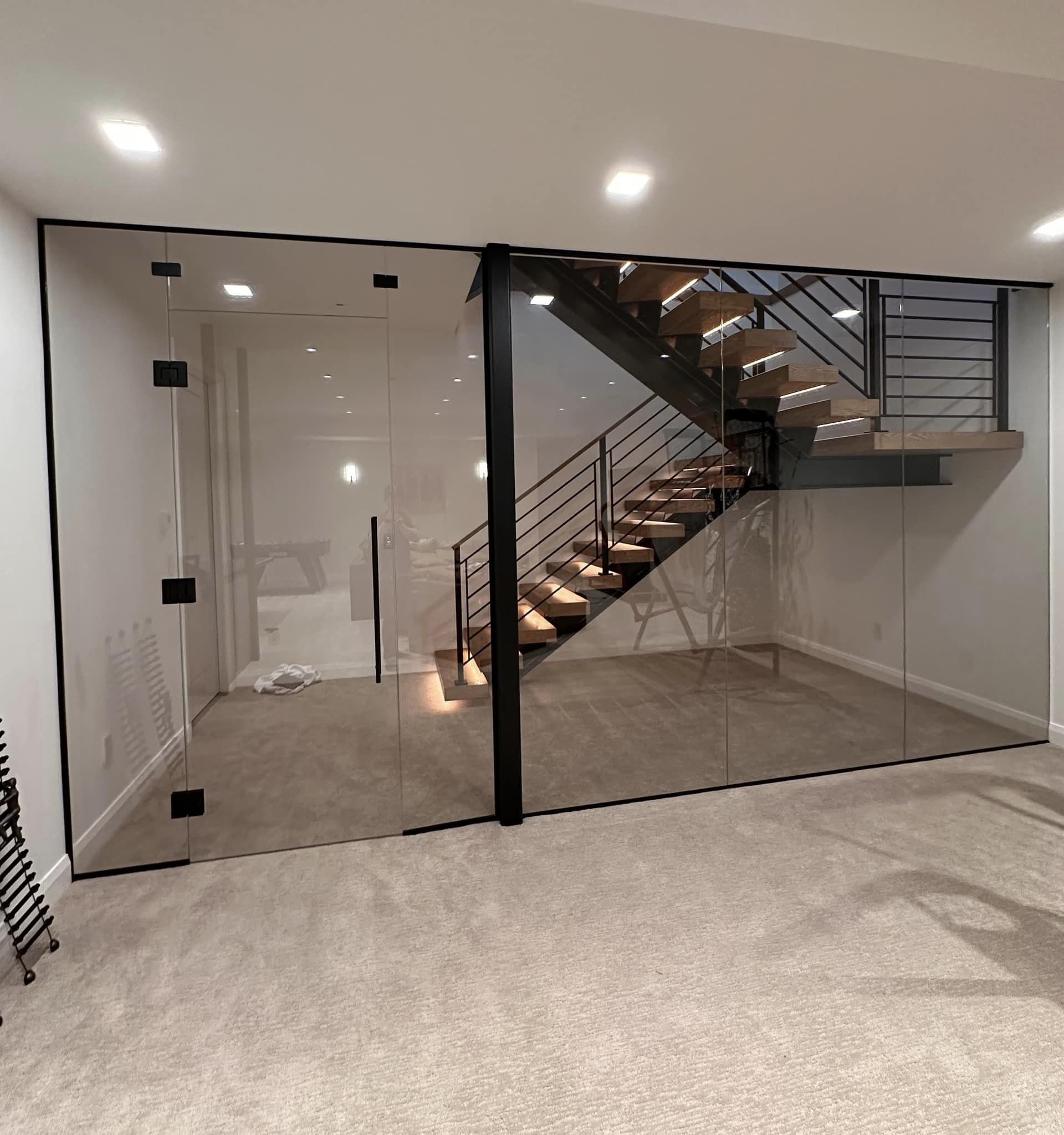 Modern interior with glass partition and wooden staircase in basement