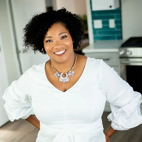 Photo of Nikita Allen, smiling and standing in a modern kitchen.