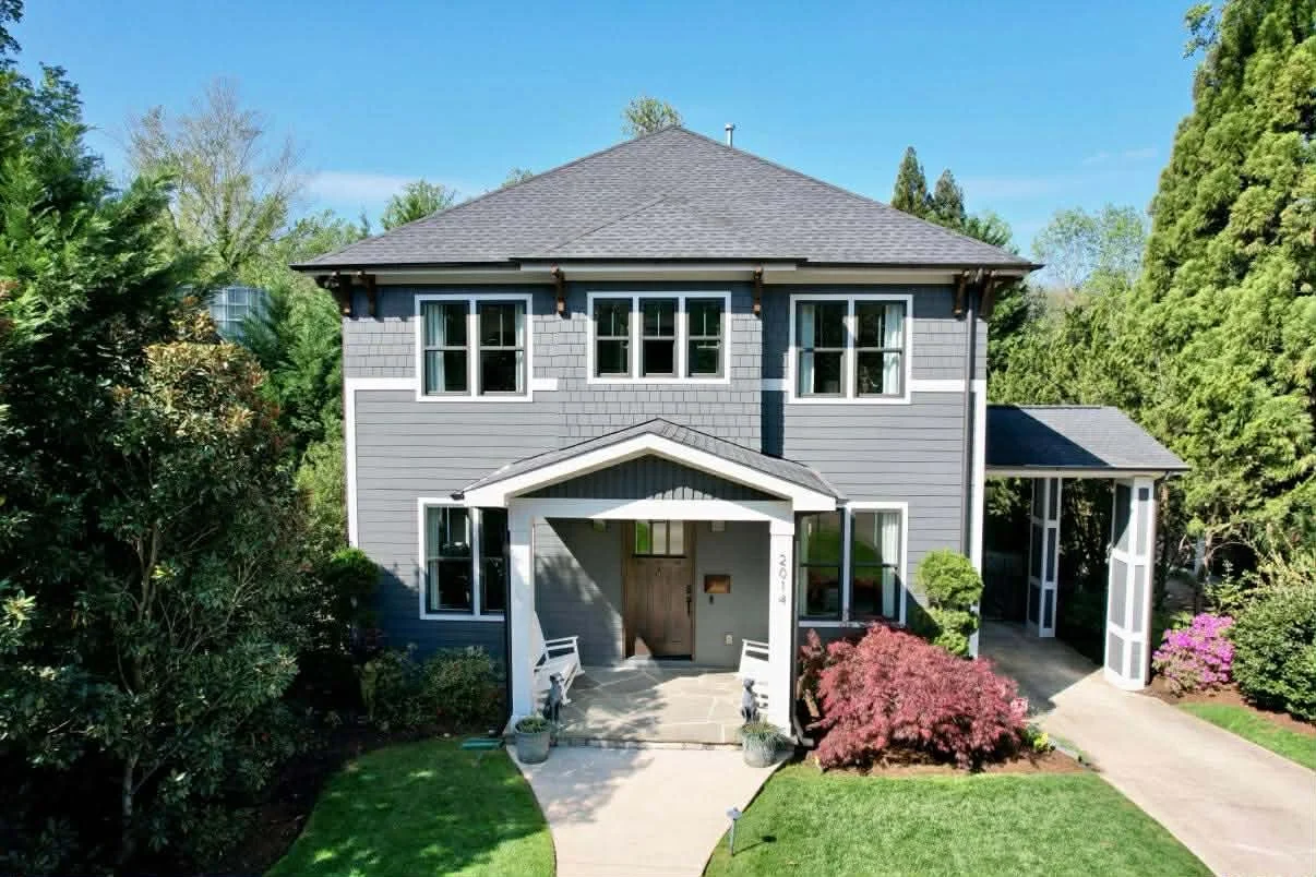 Freshly painted two-story home in Charlotte, NC with gray exterior siding, white trim, updated windows, and landscaped front yard, showcasing professional exterior painting work.