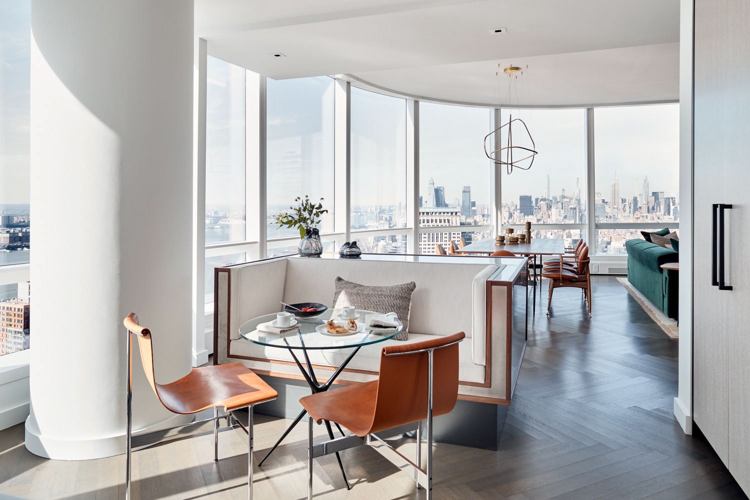 Modern apartment interior with large windows and city view, featuring a dining area with chairs, a glass table, and a couch; contemporary decor with sleek furniture and minimalistic design.