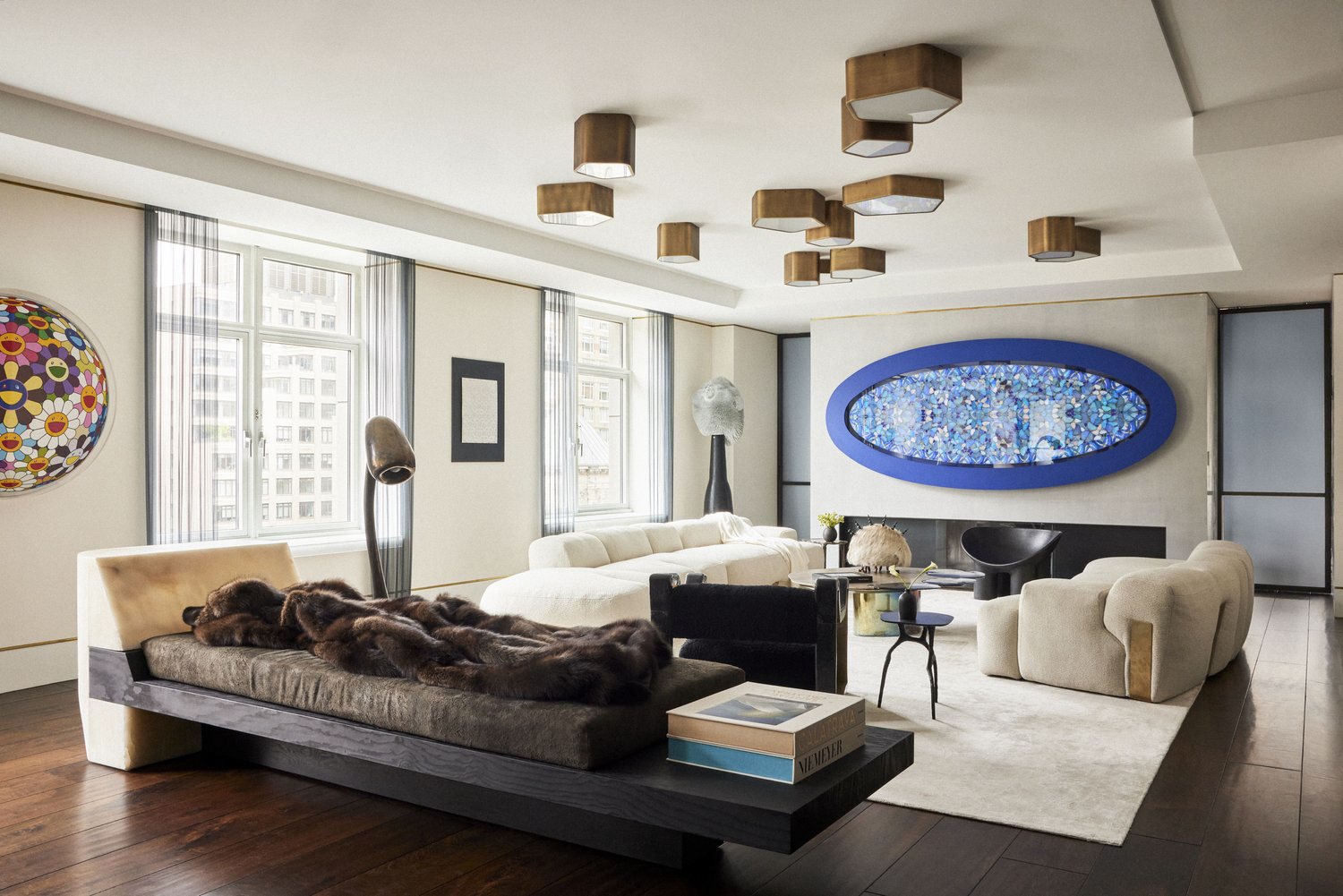 Modern living room with contemporary furniture and artwork, including a plush couch, abstract wall art, and stylish lighting fixtures on the ceiling.