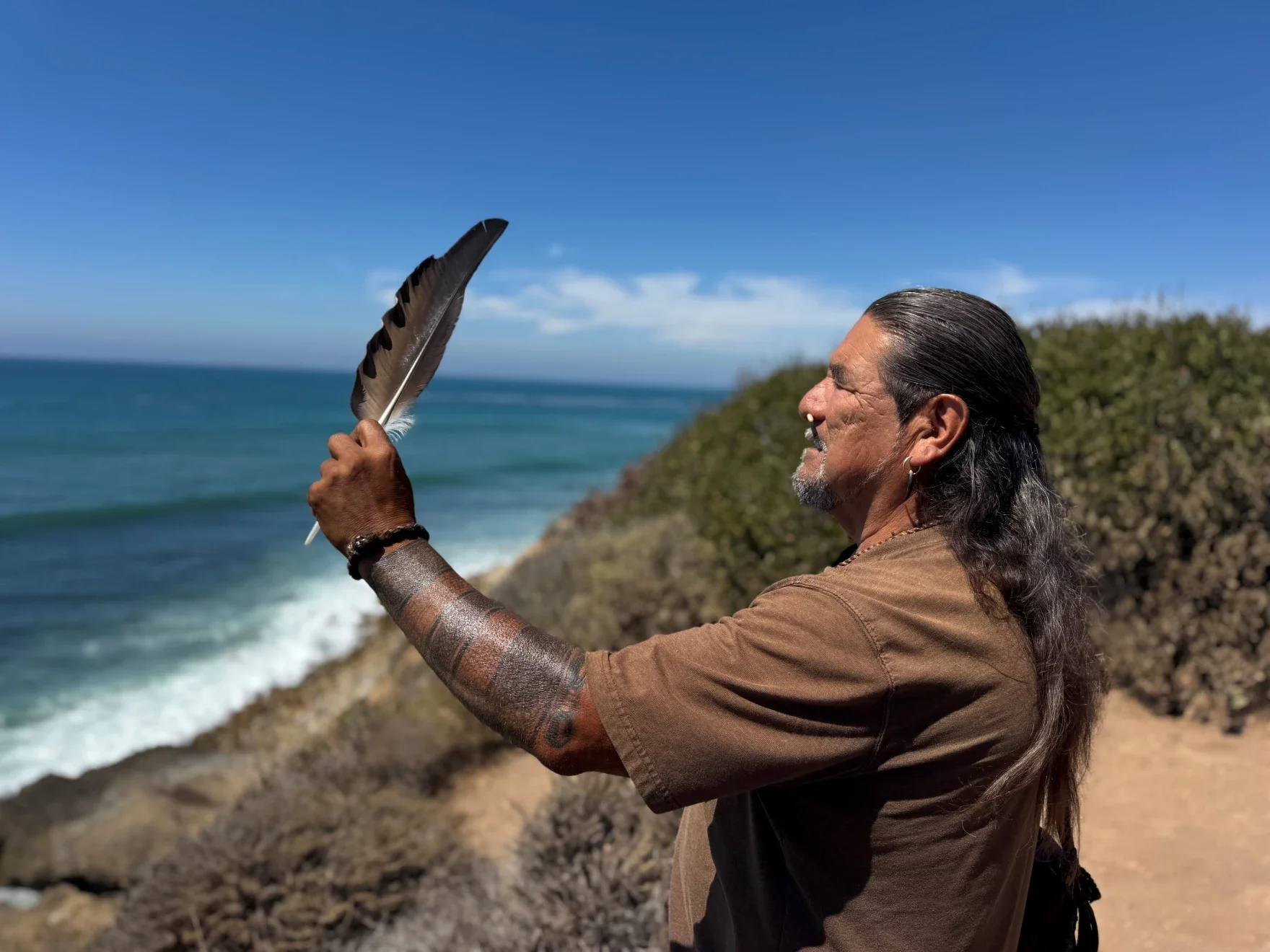 Mati holds up a feather overlooking the ocean. Photo by Caroline Feraday/KCLU.