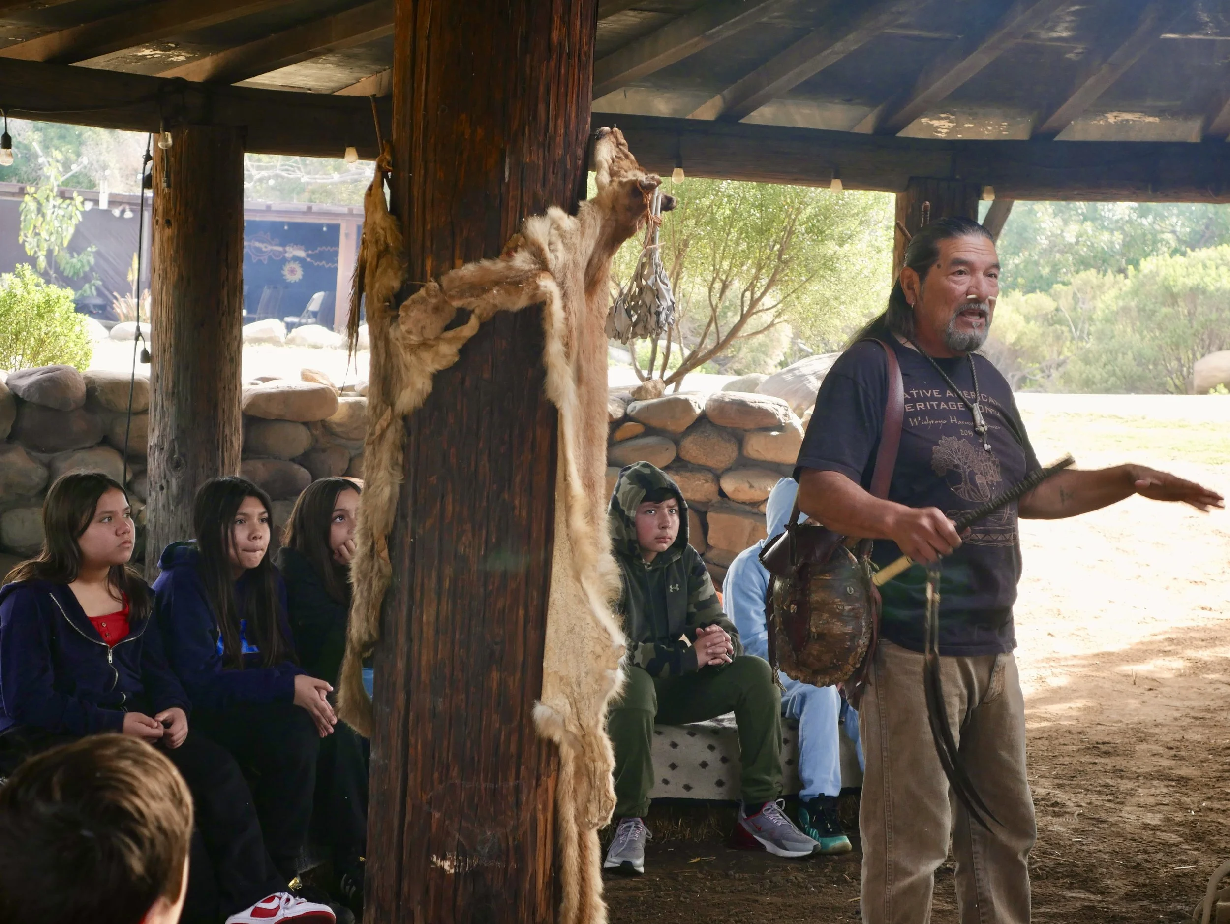 Mati Waiya standing inside the sil'i'yik teaching a group of students.