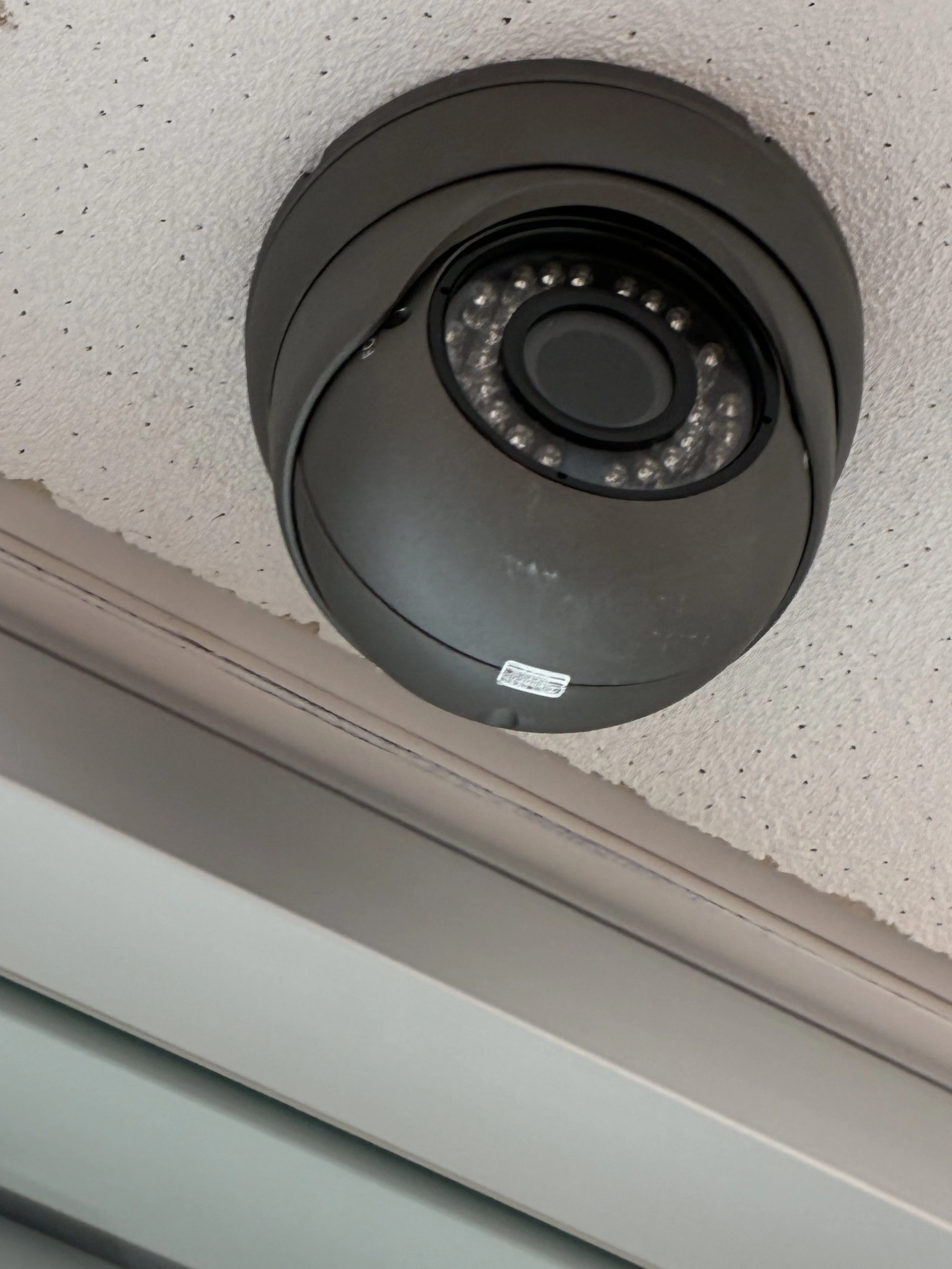 Close-up of a black security camera mounted on a ceiling.