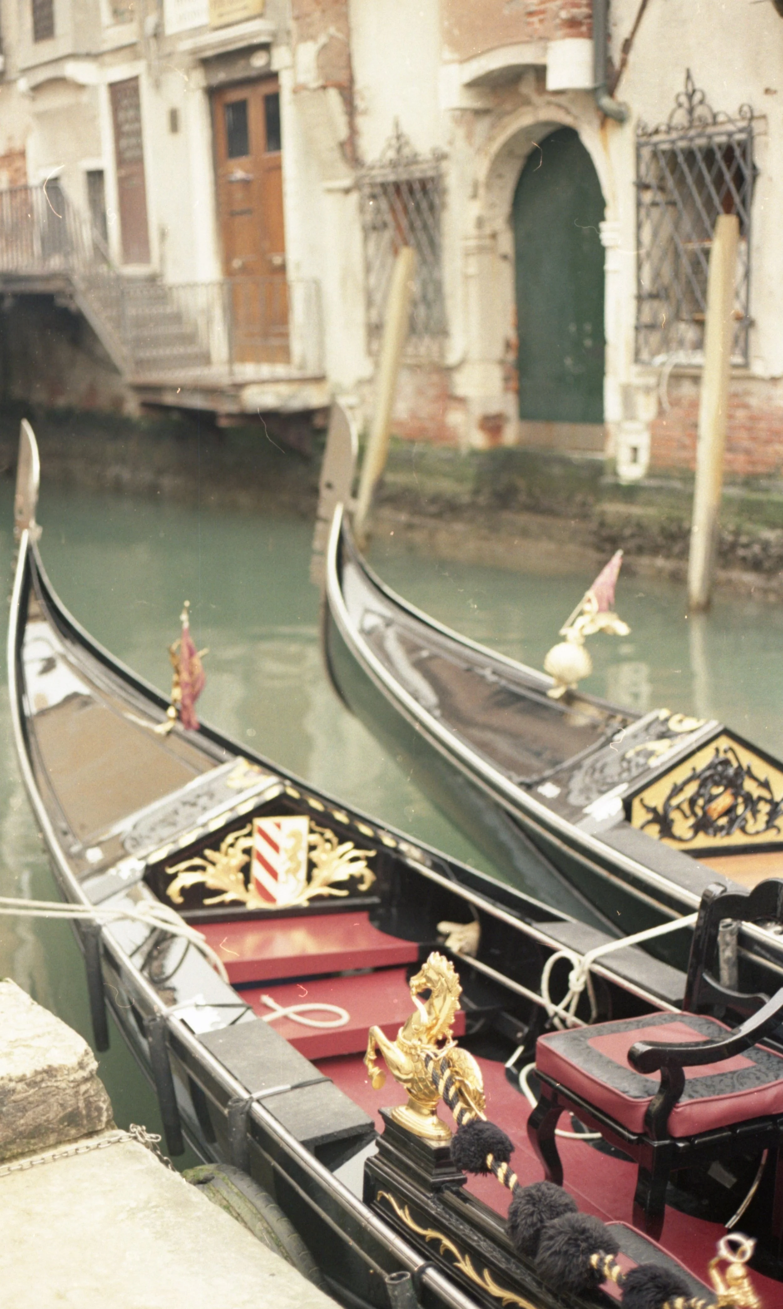 Gondolas docked along a canal with old brick buildings in Venice, Italy.