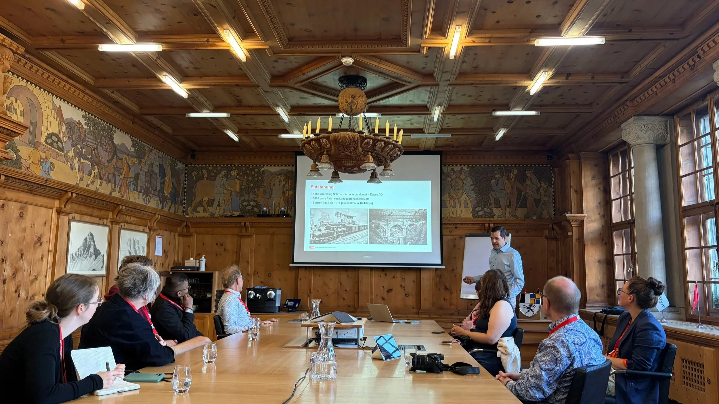 People in a wood-paneled room looking at a presentation