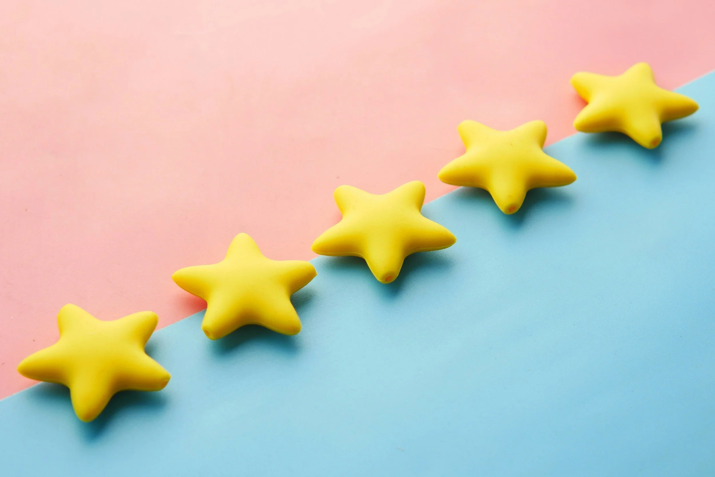 Six yellow star-shaped objects arranged in a line on a two-toned pink and blue background.