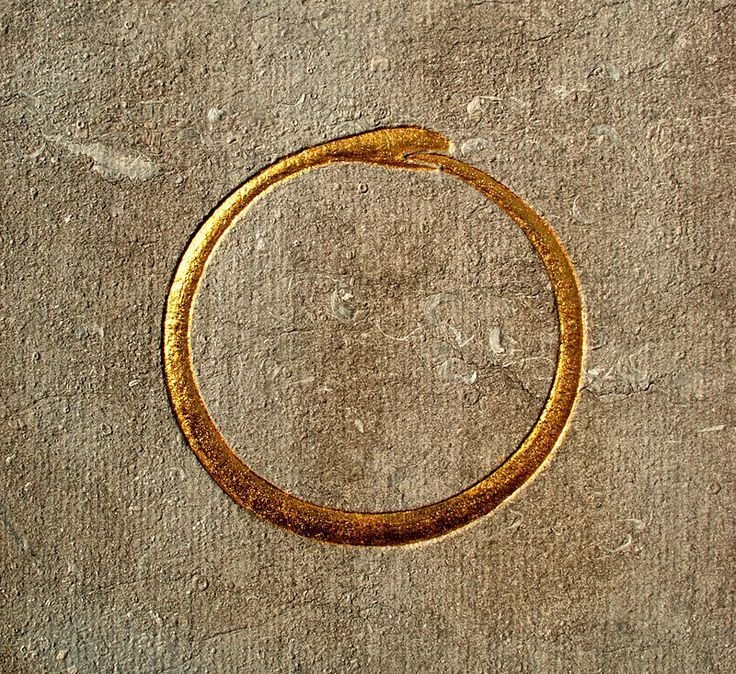 A worn, gold-colored metal ring lying on a rough, concrete surface.