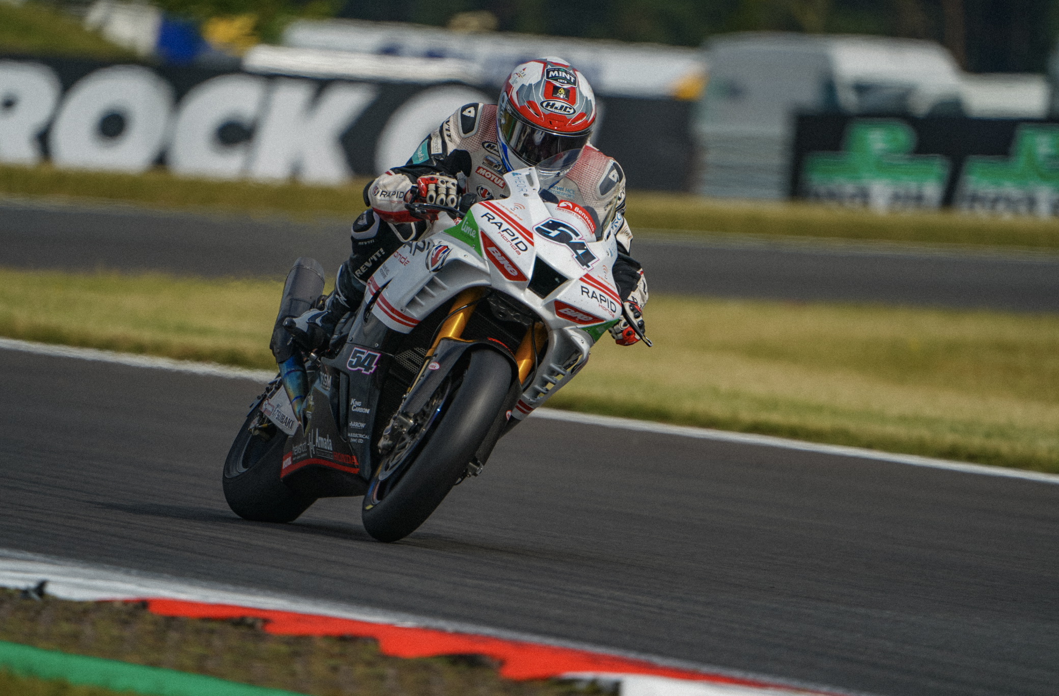 Motorcycle racer leaning into a turn on a racetrack during a race.