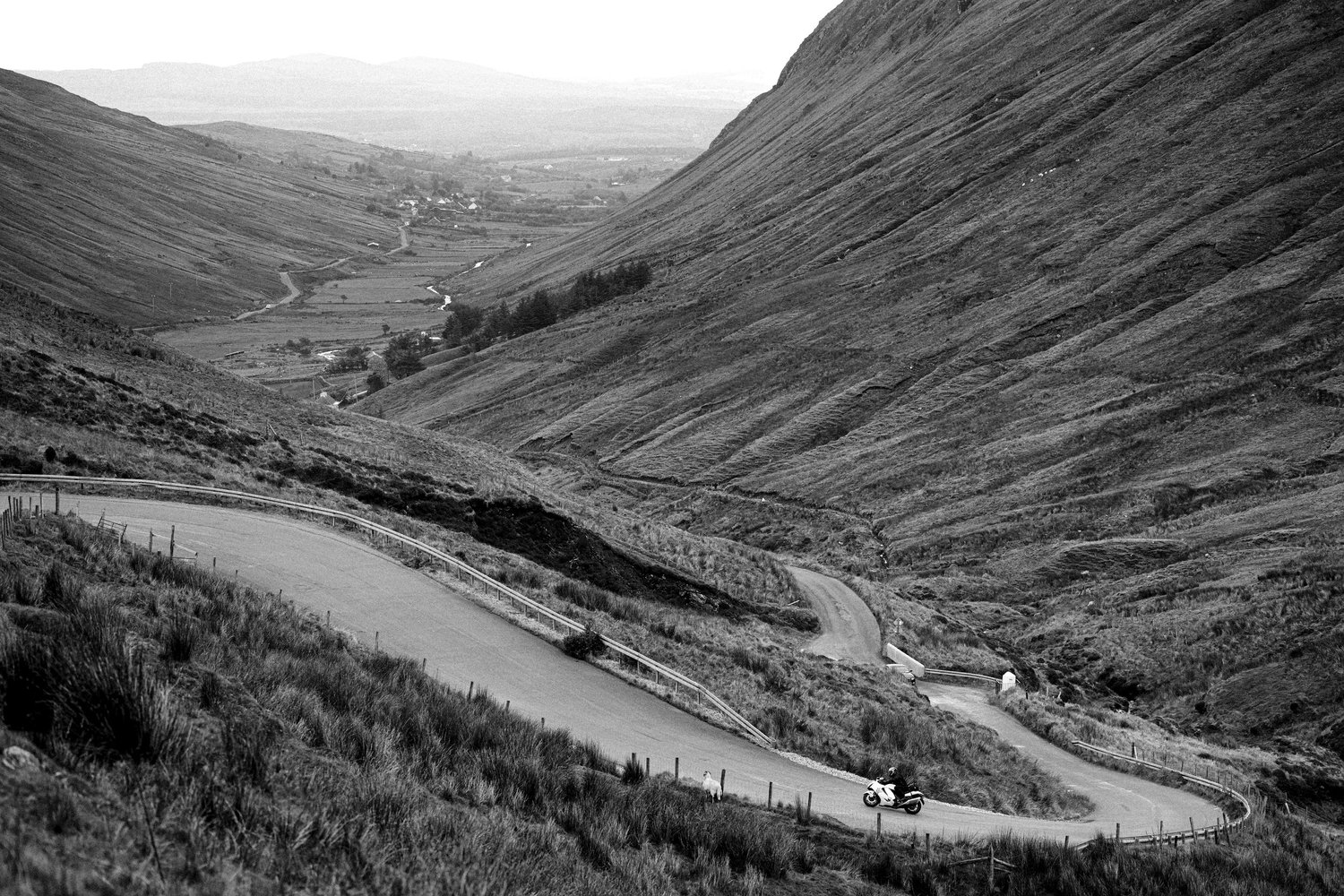 A rider on a winding road between steep hillsides