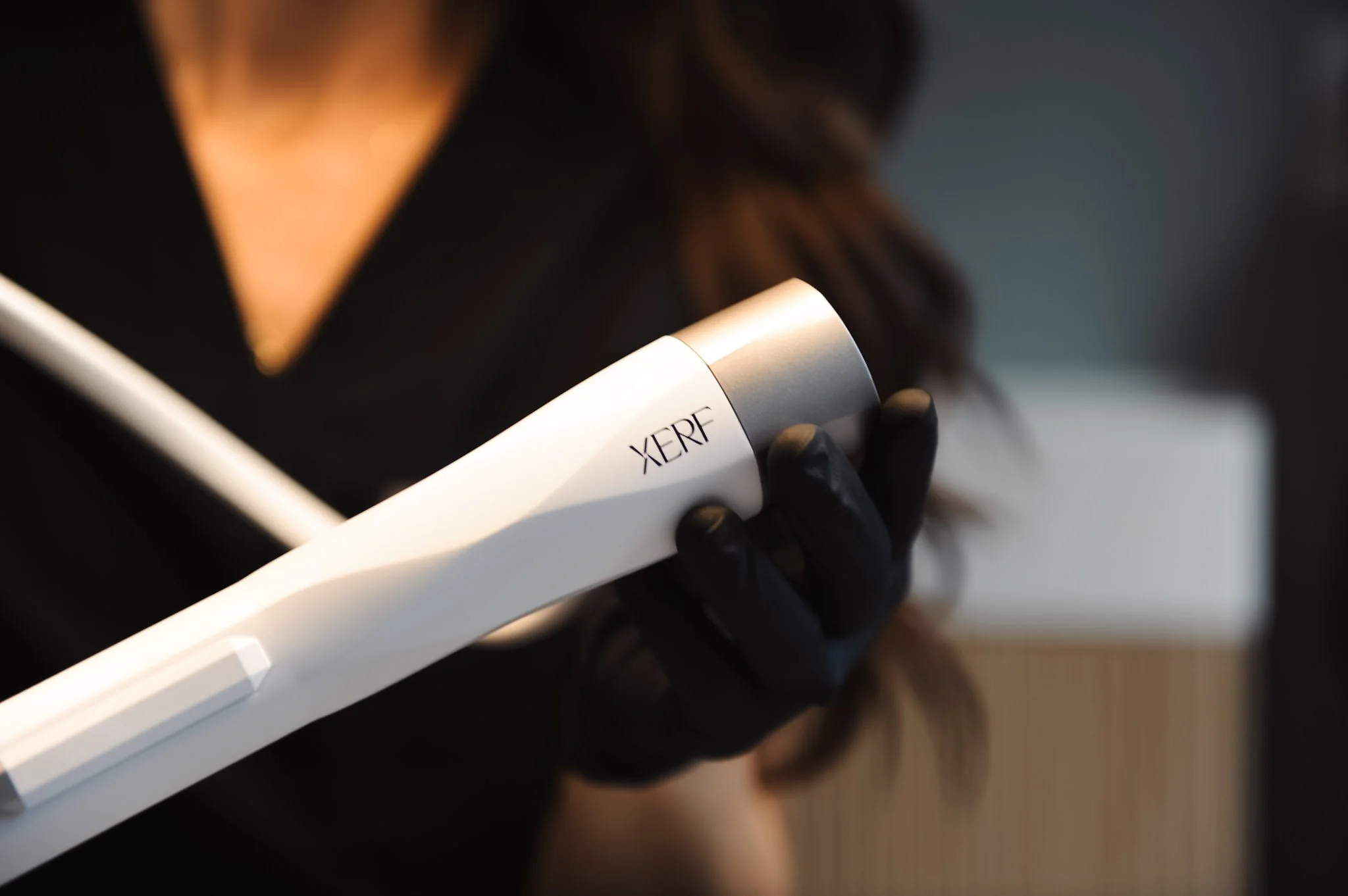 female in black scrubs holding a XERF hand held piece
