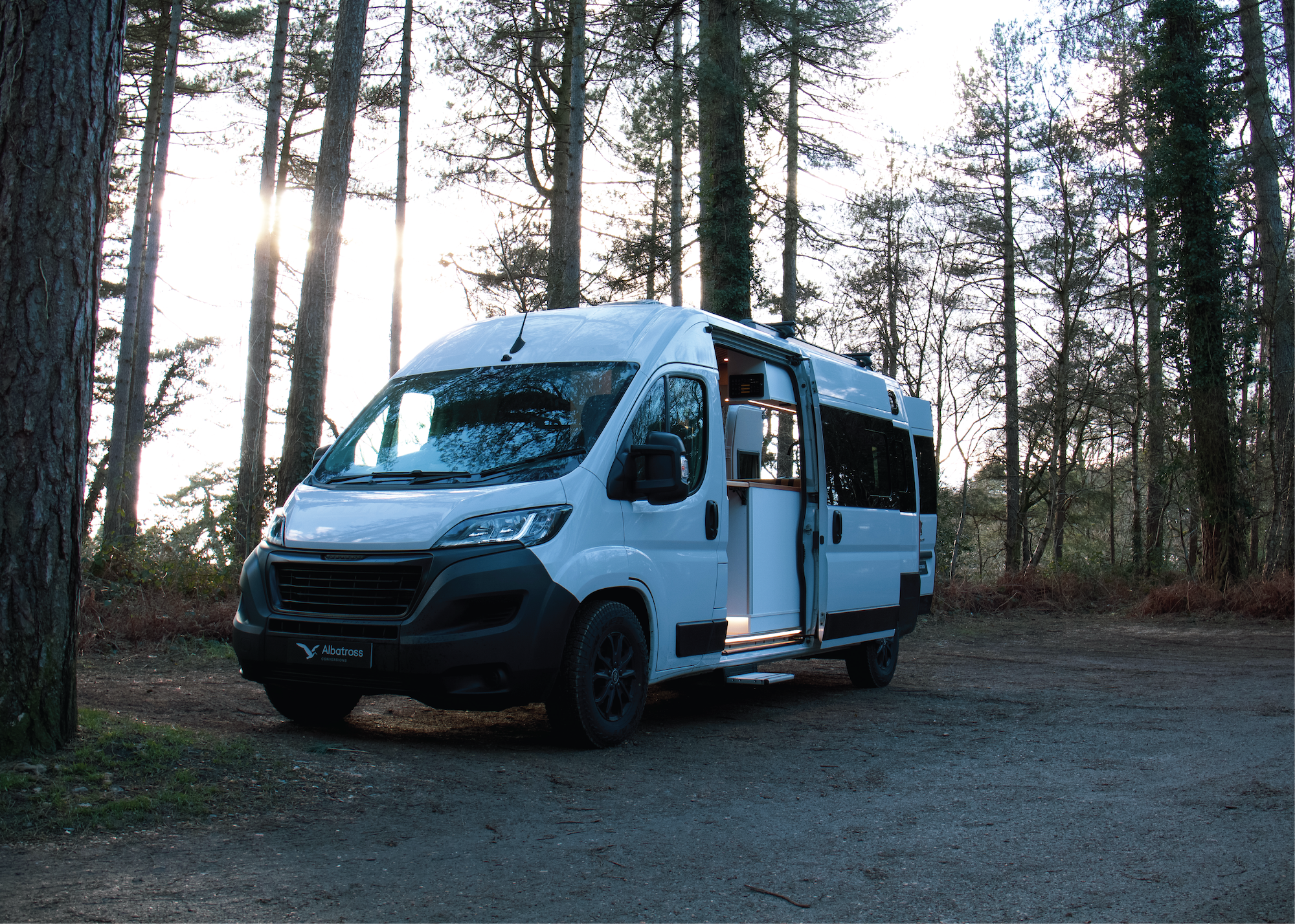 Bespoke white Albatross Conversions Peugeot Boxer Wander campervan parked in a bright forest clearing.