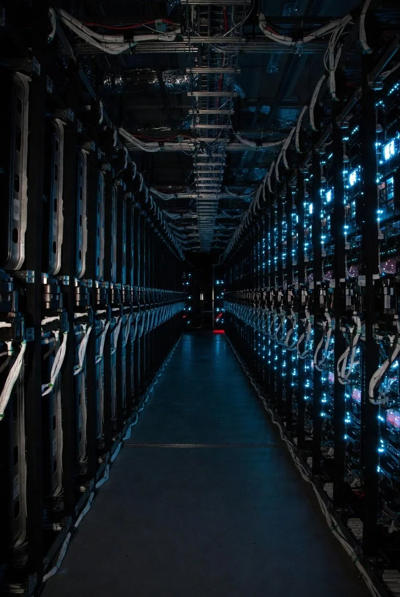 A data center aisle with server racks on both sides and illuminated blue indicator lights.