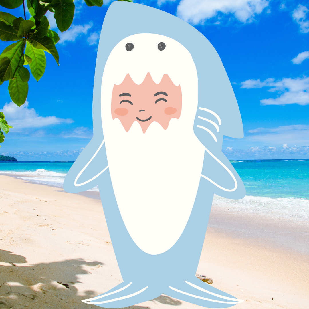 Cartoon character of a smiling person dressed in a shark costume on a beach with blue sky and ocean.