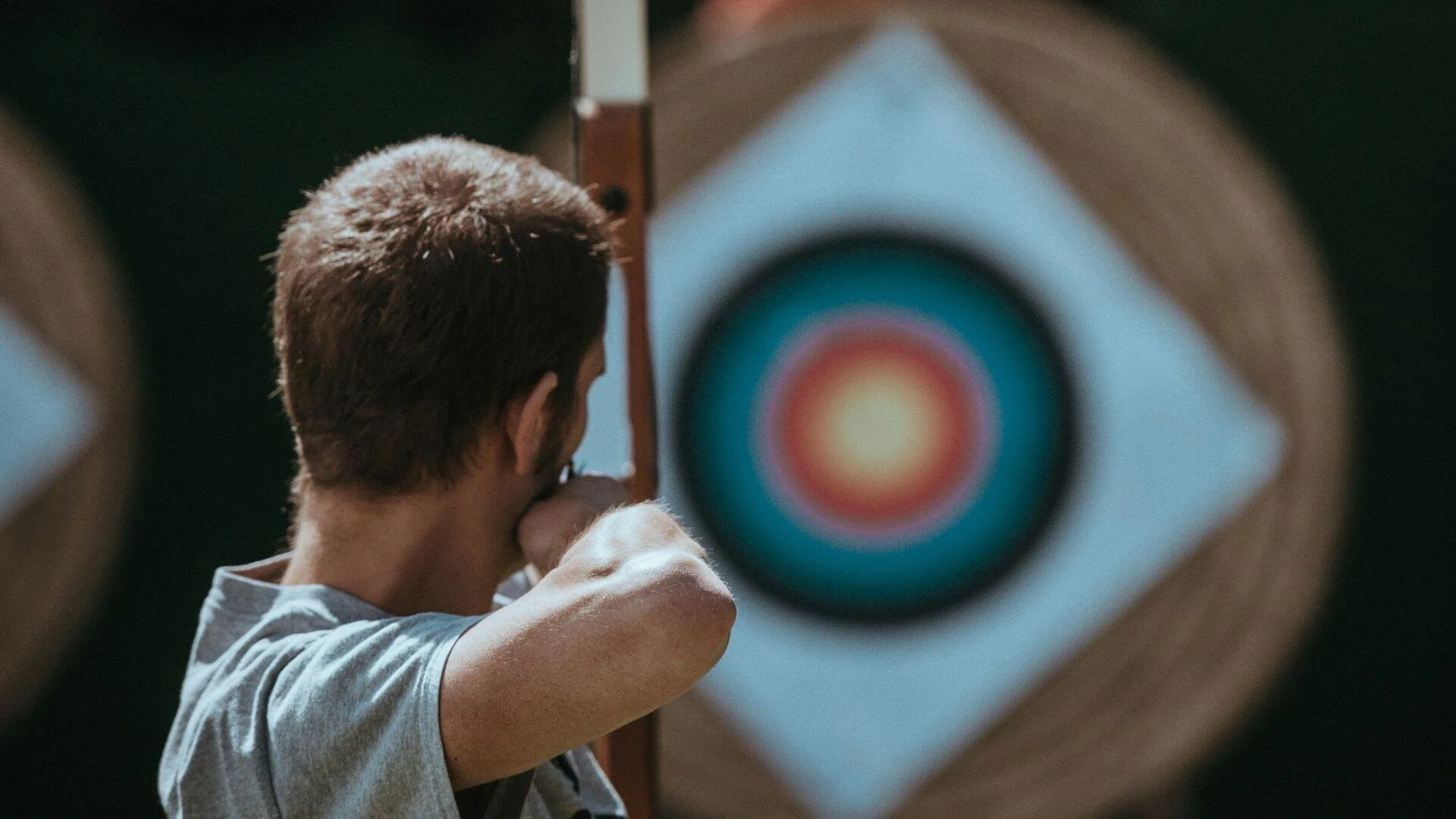 A person holding a bow and arrow and attempting to hit the target