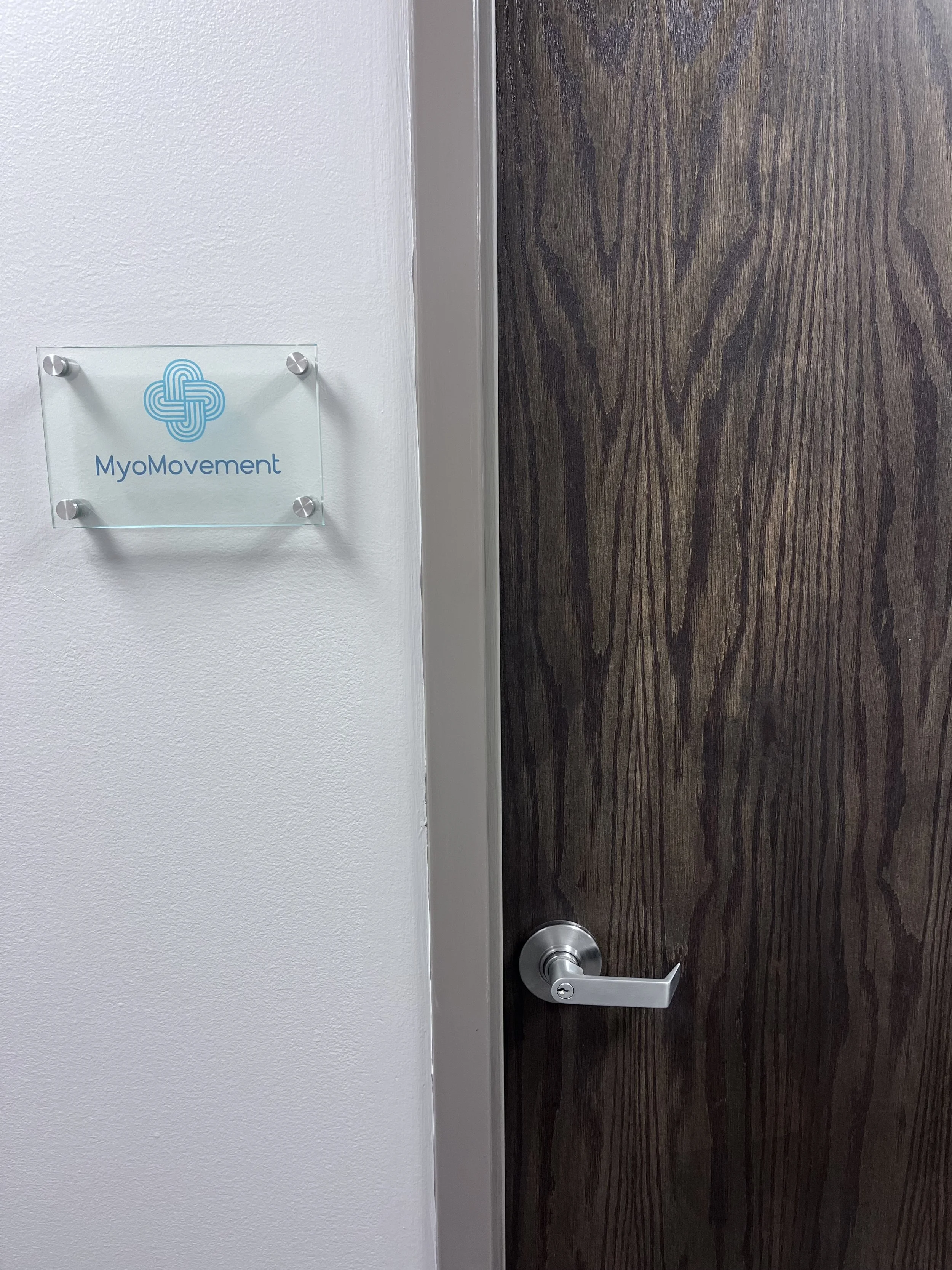 An interior office door with a MyoMovement sign on the wall beside it.