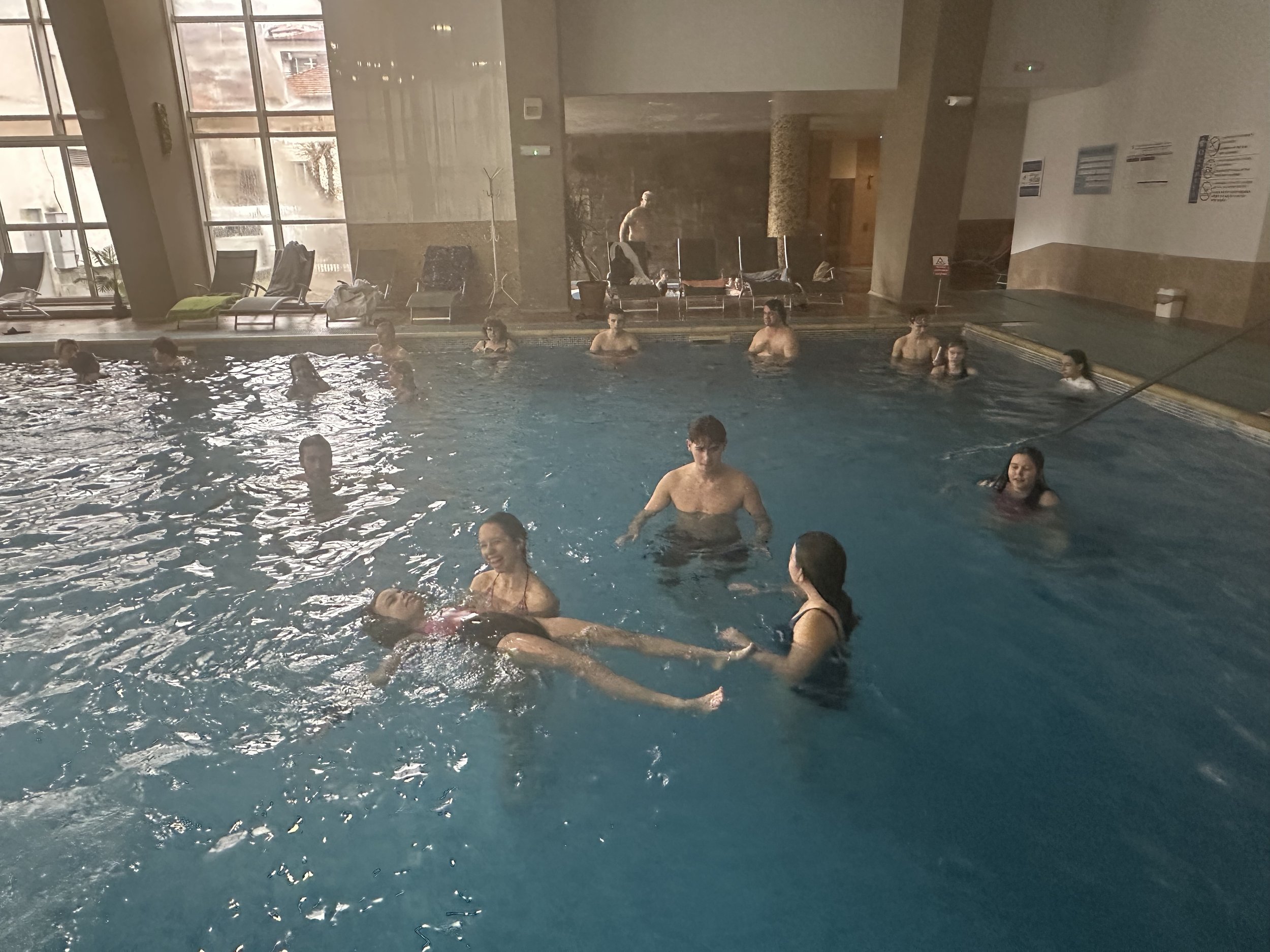 People swimming and relaxing in an indoor swimming pool.