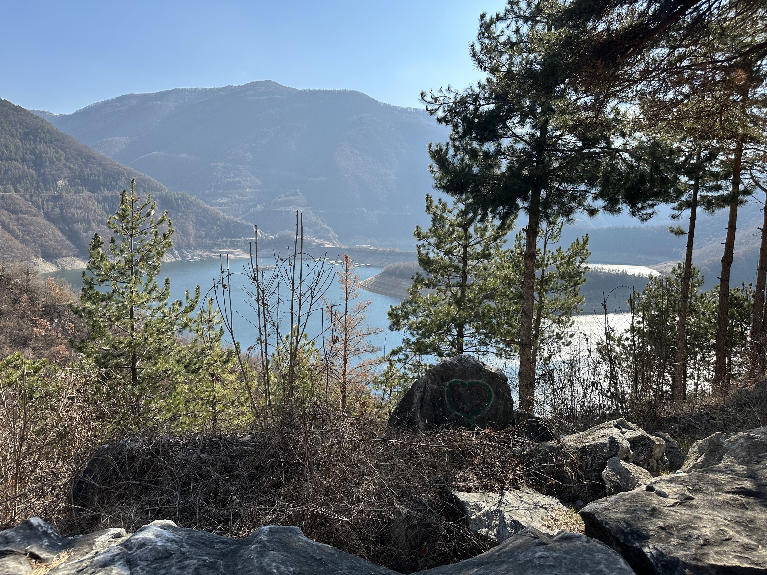 Mountain landscape with lake, trees, and rock with heart graffiti