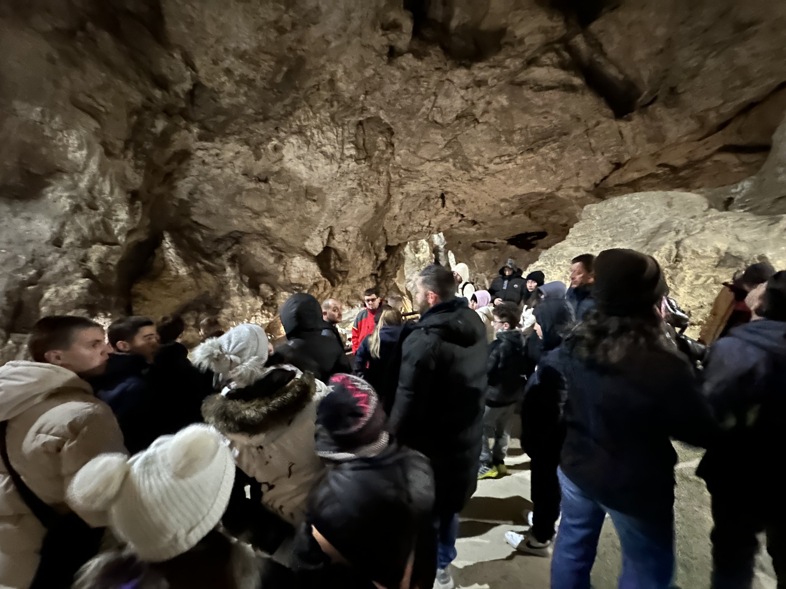 A group of people gathered inside a cave, wearing winter clothing.