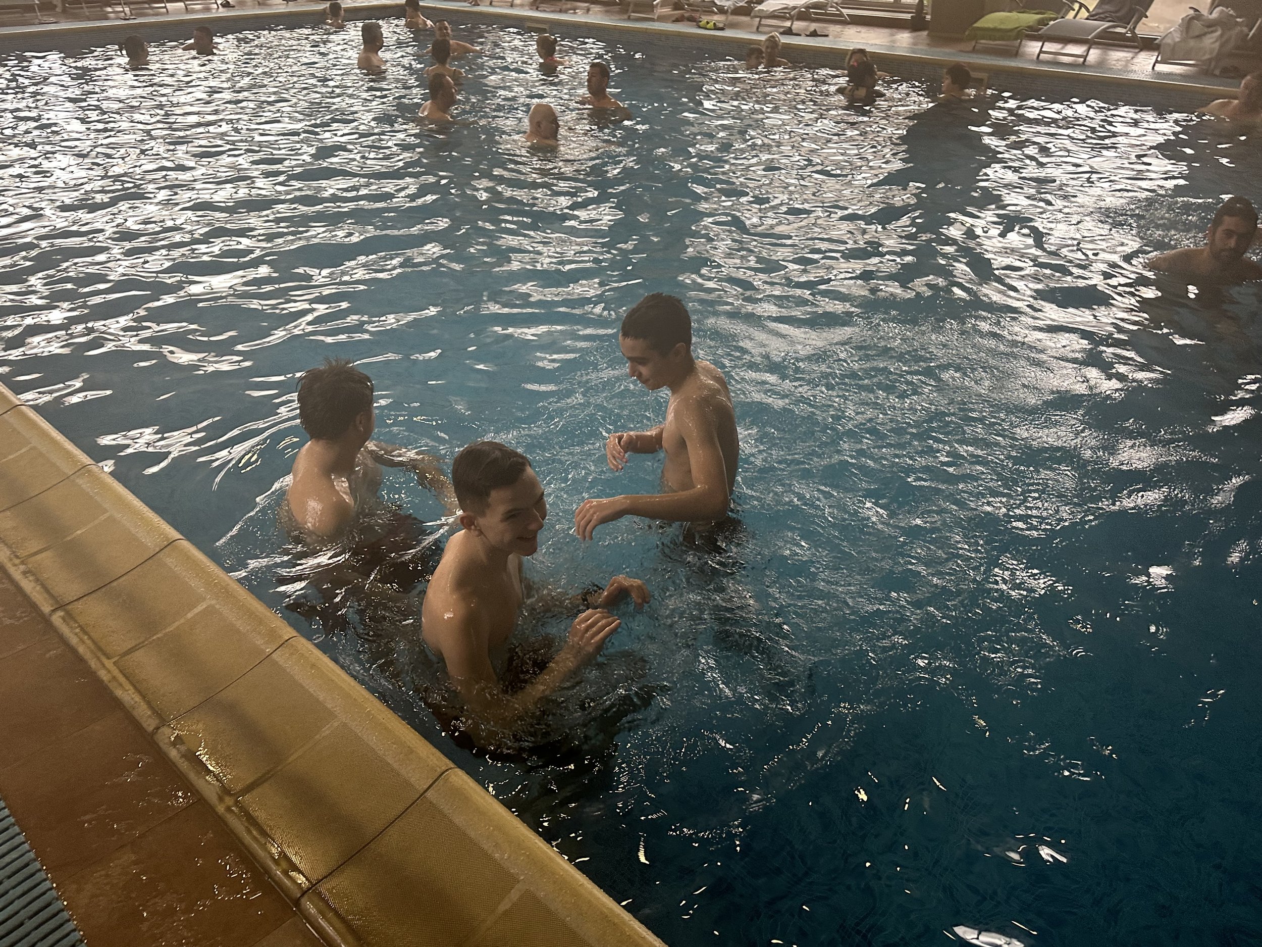 Indoor swimming pool with several people swimming and standing in the water.