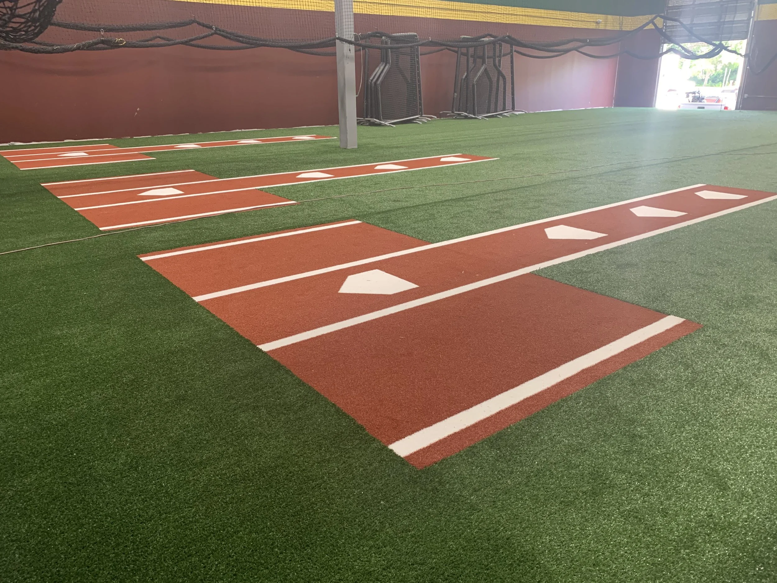 Indoor baseball training facility with artificial turf and pitching lanes