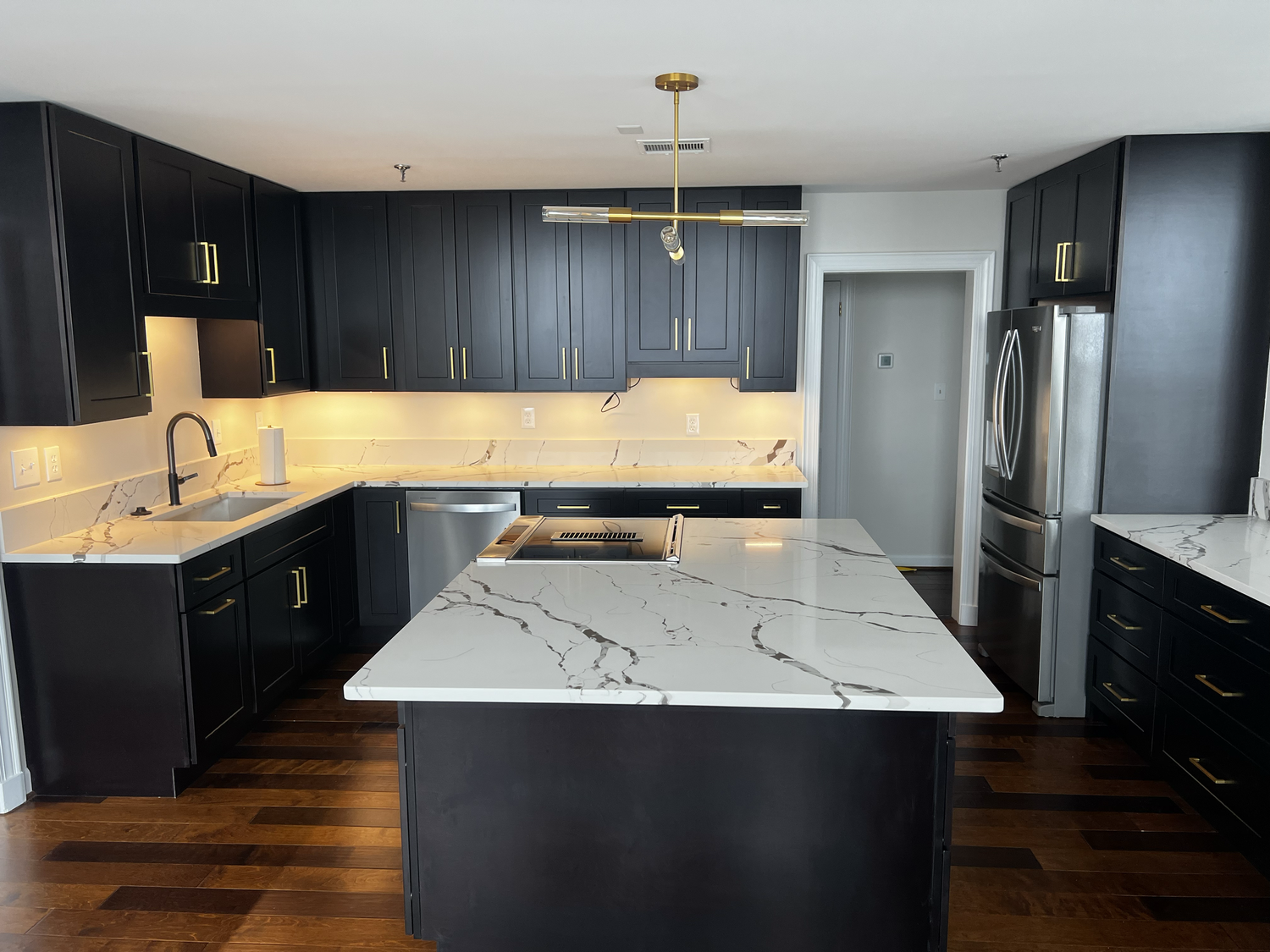 White veined island and perimeter countertops in a dark-cabinet kitchen by Sondos Stone