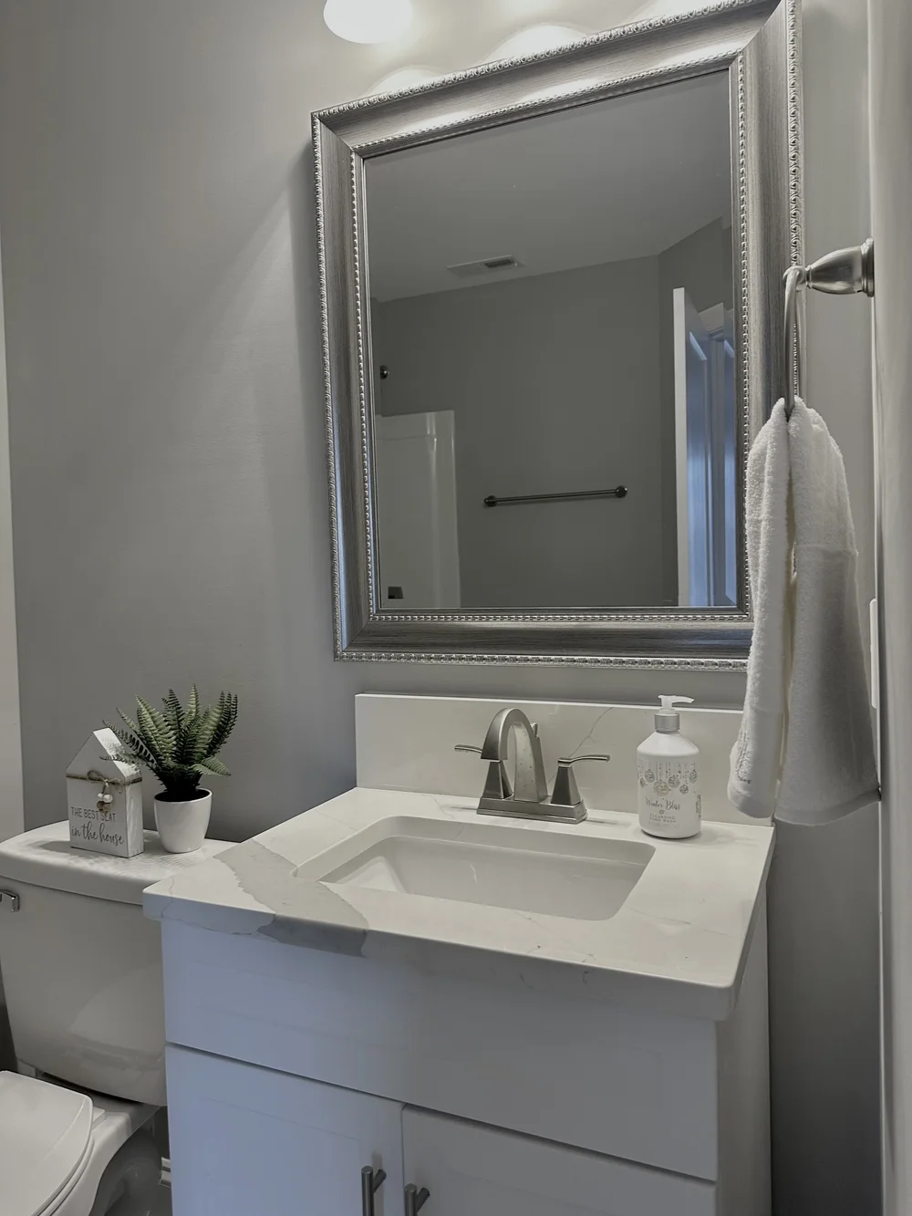 Small white veined vanity top with an undermount rectangular sink and rear stone backsplash