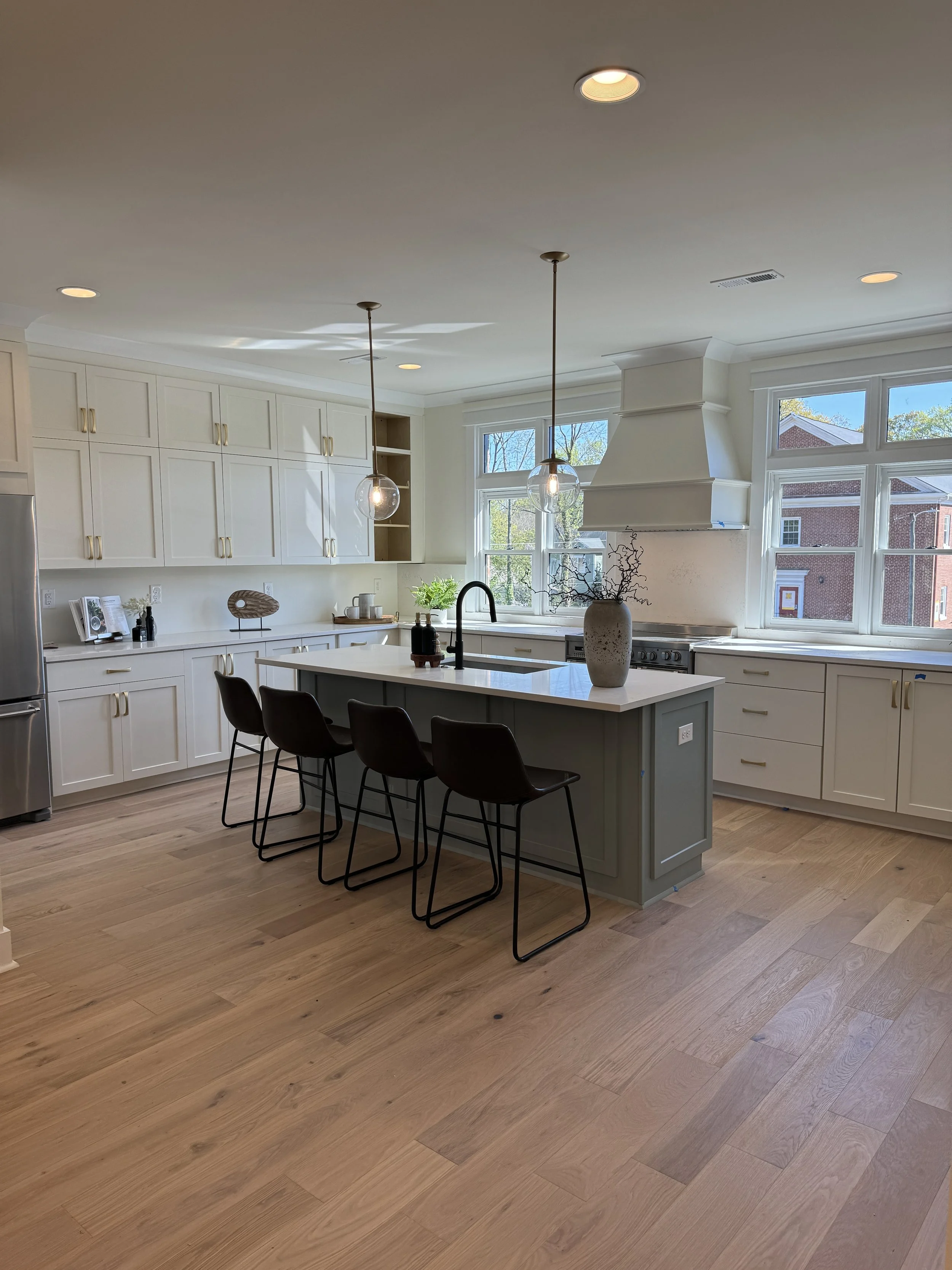 White kitchen with a gray island, brass accents and bright countertops