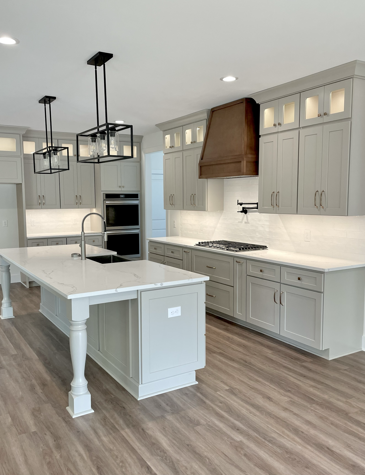 Light-gray kitchen with a warm wood hood and bright island countertops