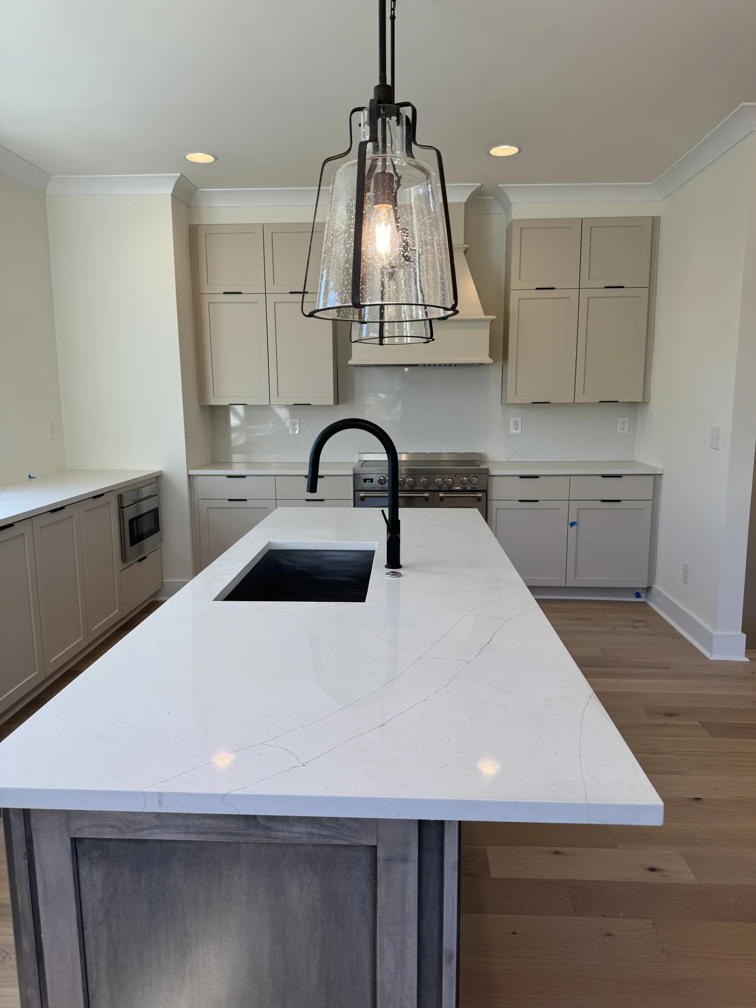 Sondos Stone kitchen island with a black sink, black faucet and lightly veined countertop