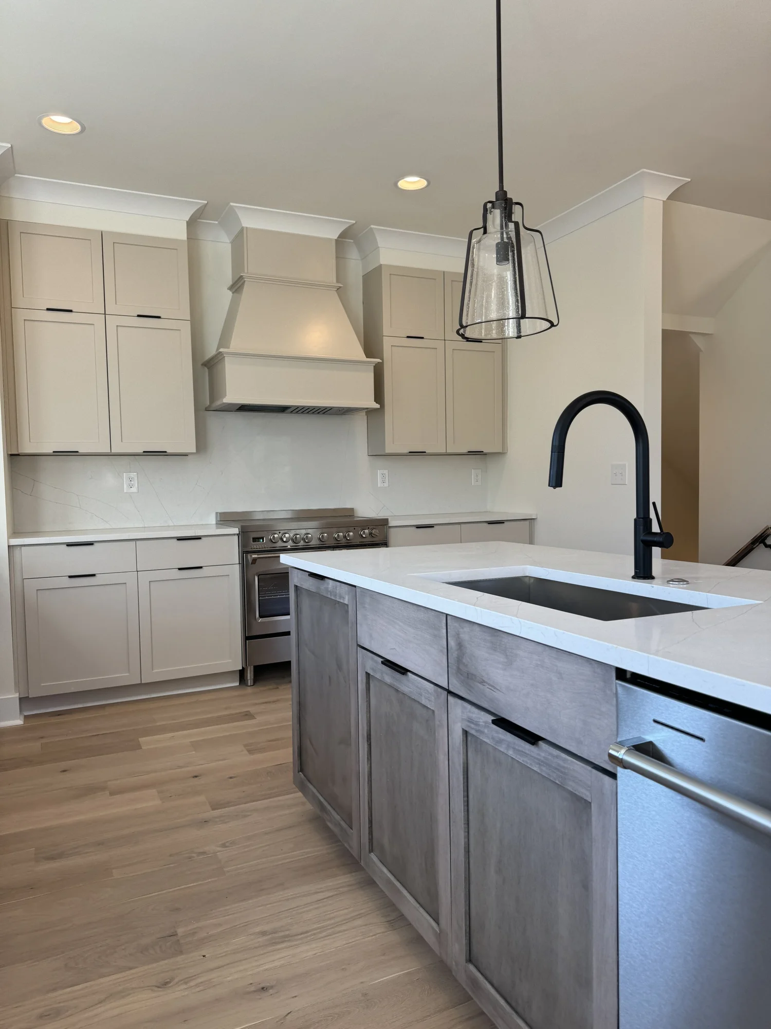 Wide angle of the same kitchen with a gray island and light counters