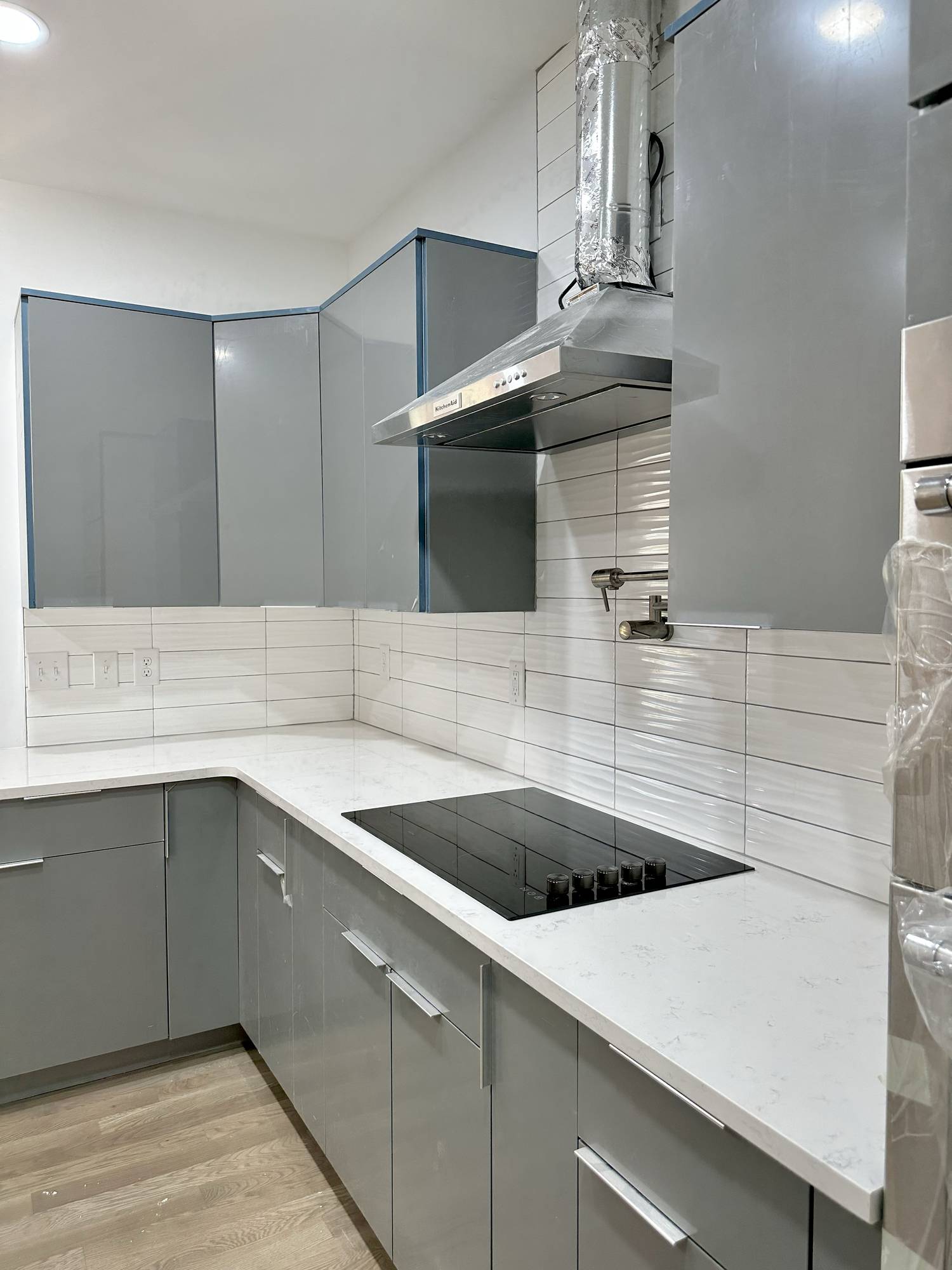 Sondos Stone kitchen project with gray cabinets cooktop and stone backsplash